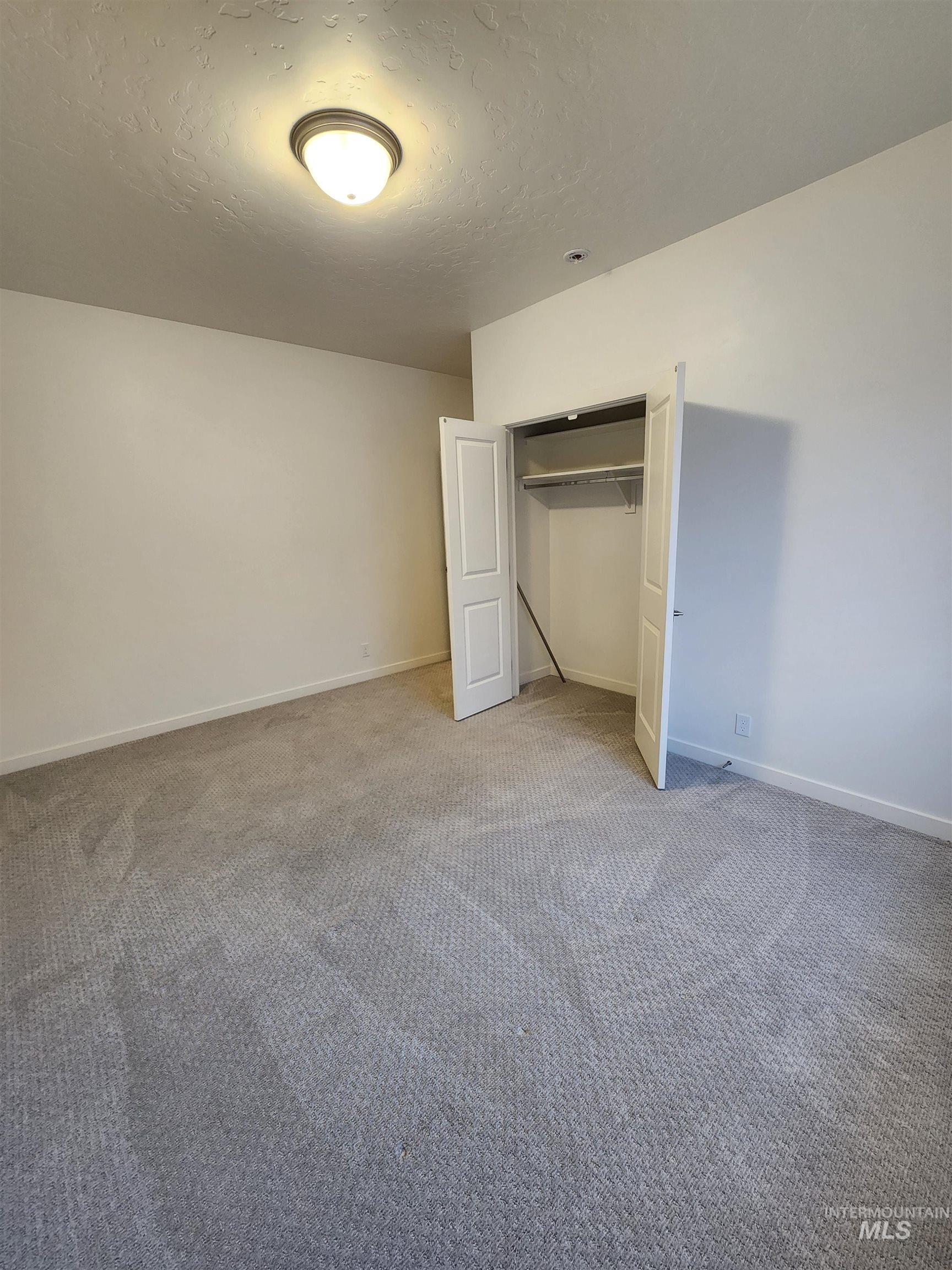 Unfurnished bedroom featuring a textured ceiling, carpet, and a closet