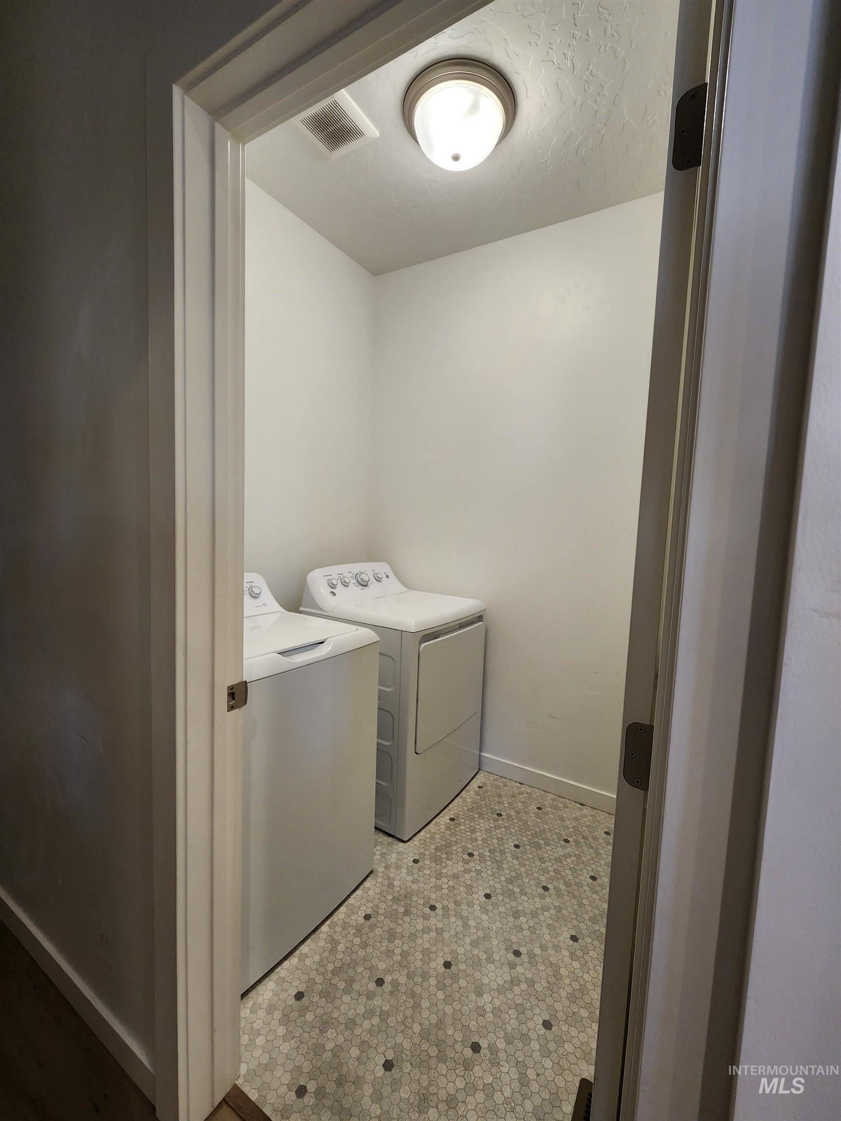 Laundry area featuring washer and clothes dryer and a textured ceiling