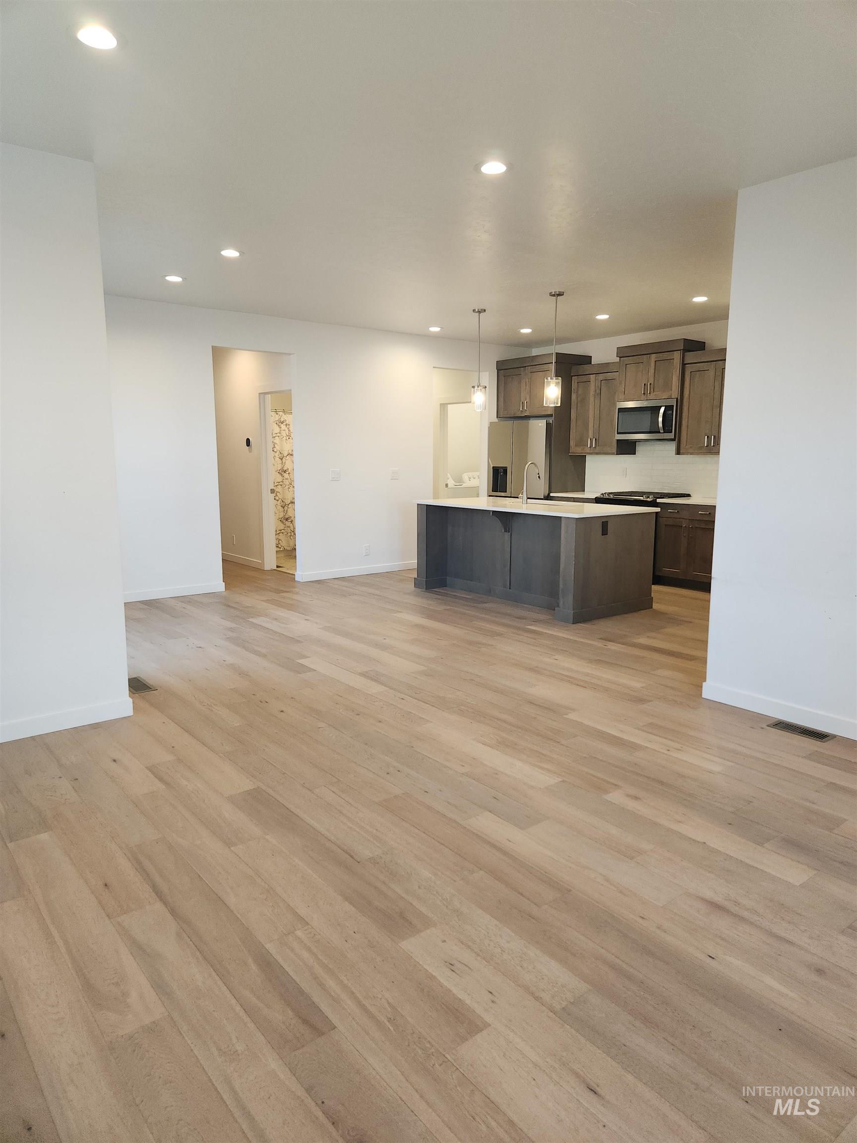 Kitchen featuring open floor plan, recessed lighting, a breakfast bar, light wood-style floors, and a kitchen island with sink