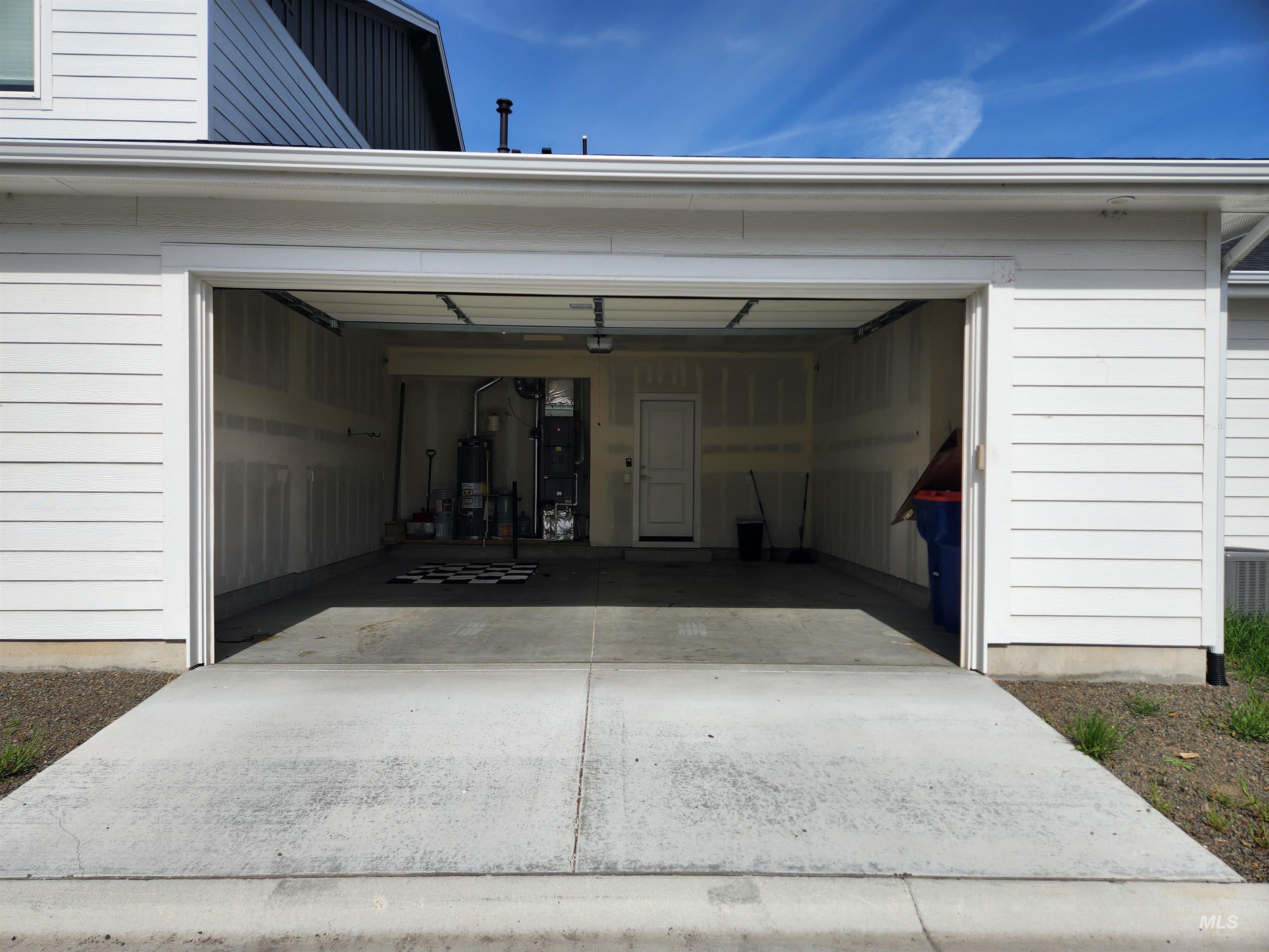 Garage featuring driveway, gas water heater, and heating unit