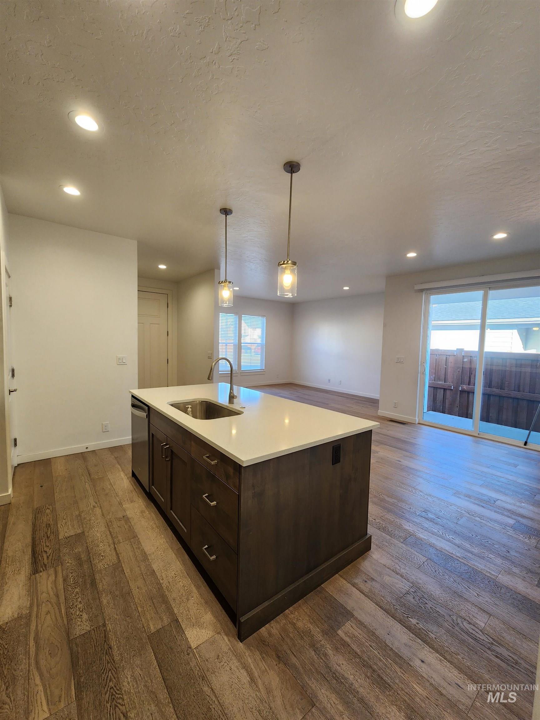 Kitchen featuring dark brown cabinets, recessed lighting, hanging light fixtures, a textured ceiling, and dark wood finished floors