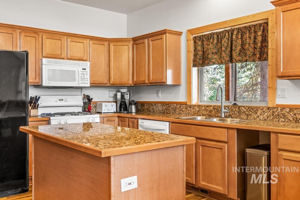 Kitchen with white appliances, tile countertops, a center island, and brown cabinets