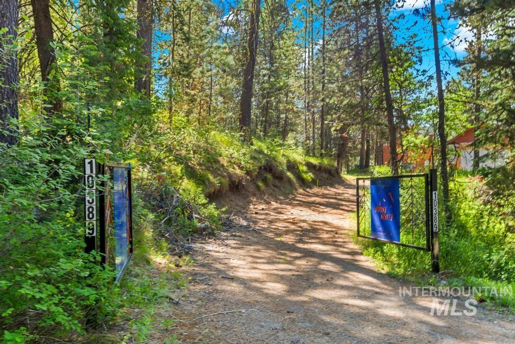 Surrounding community featuring a gate, a forest view, and dirt driveway