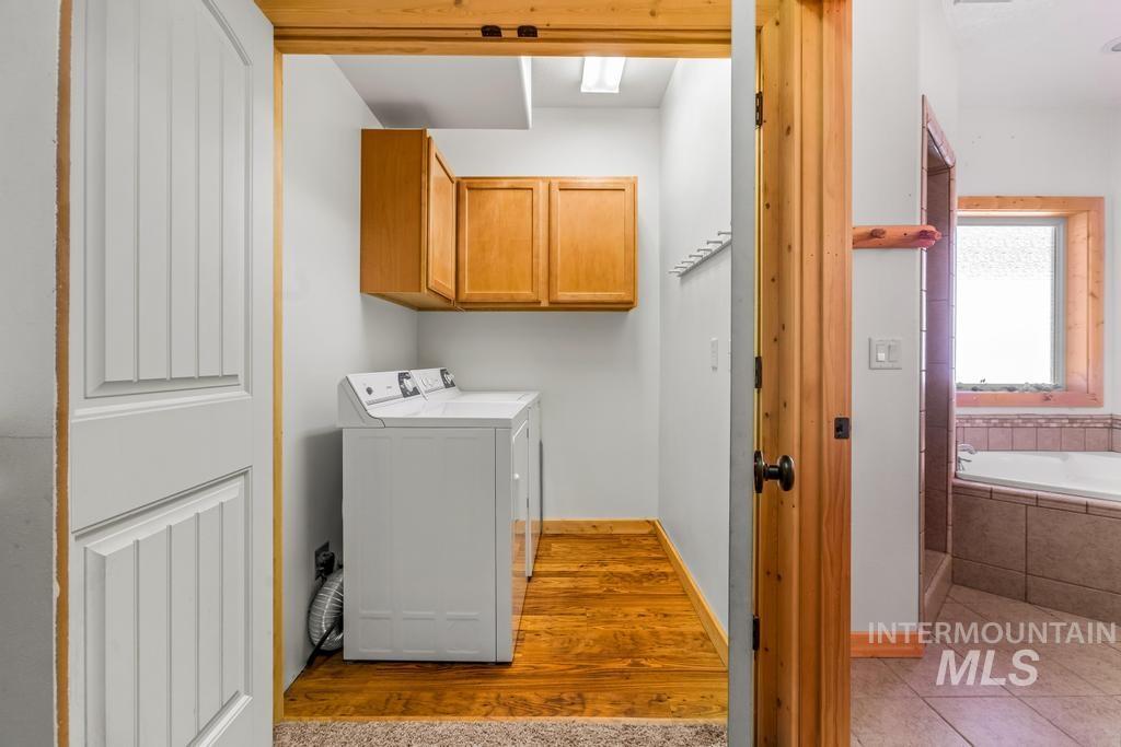 Washroom featuring cabinet space, light wood finished floors, and washing machine and dryer