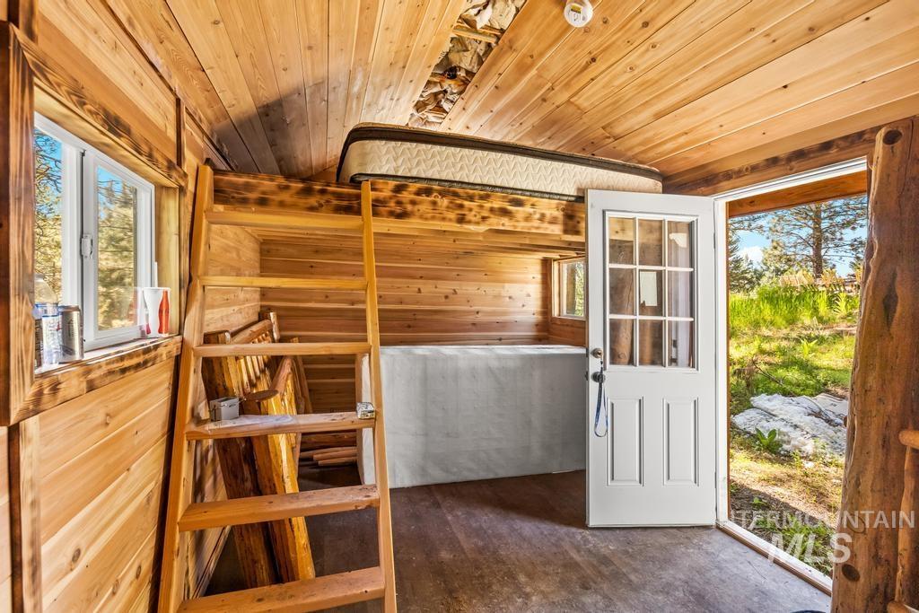 Unfurnished bedroom featuring wooden walls, dark wood-style floors, and wood ceiling
