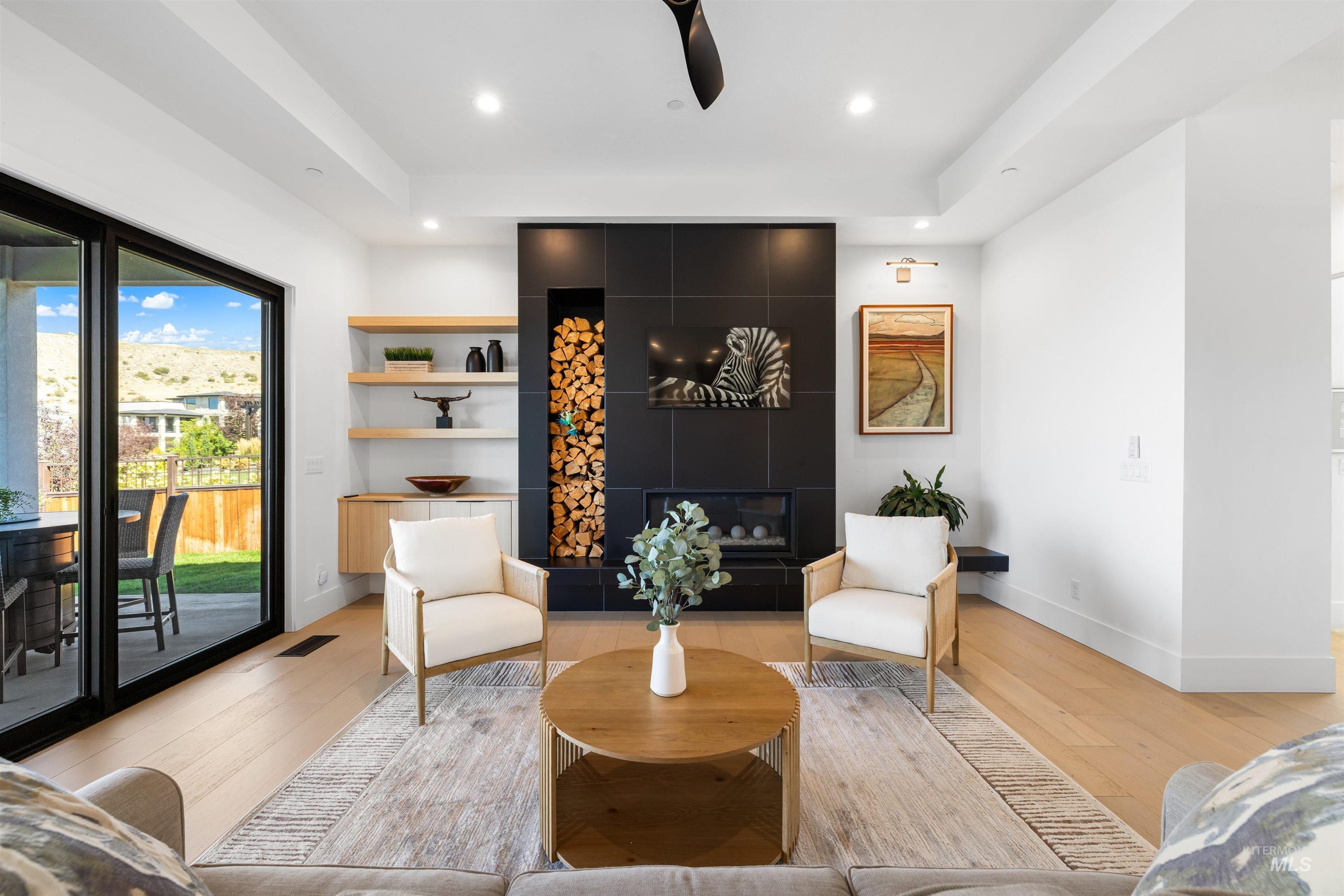 Living area with light wood finished floors, a tiled fireplace, recessed lighting, and ceiling fan