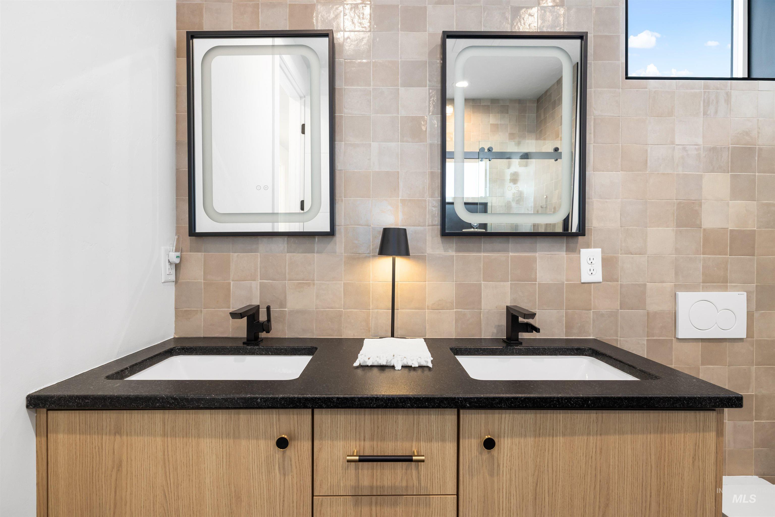Full bathroom featuring double vanity, tasteful backsplash, and tile walls