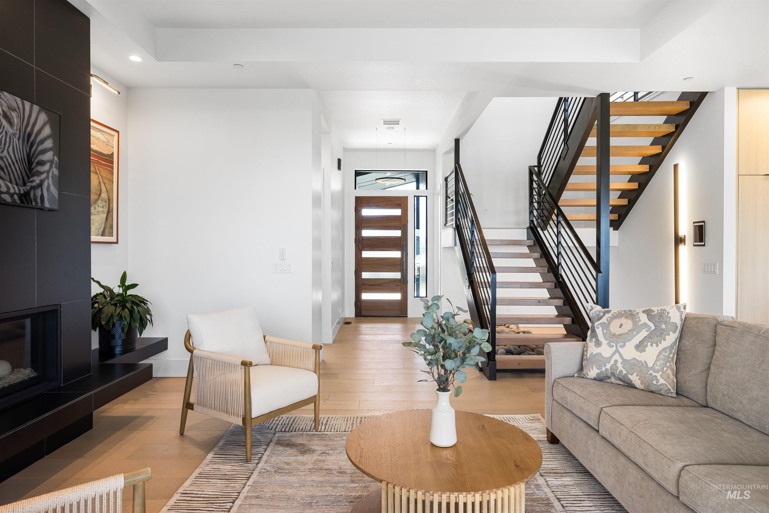 Living area featuring stairs, wood finished floors, a tiled fireplace, and recessed lighting