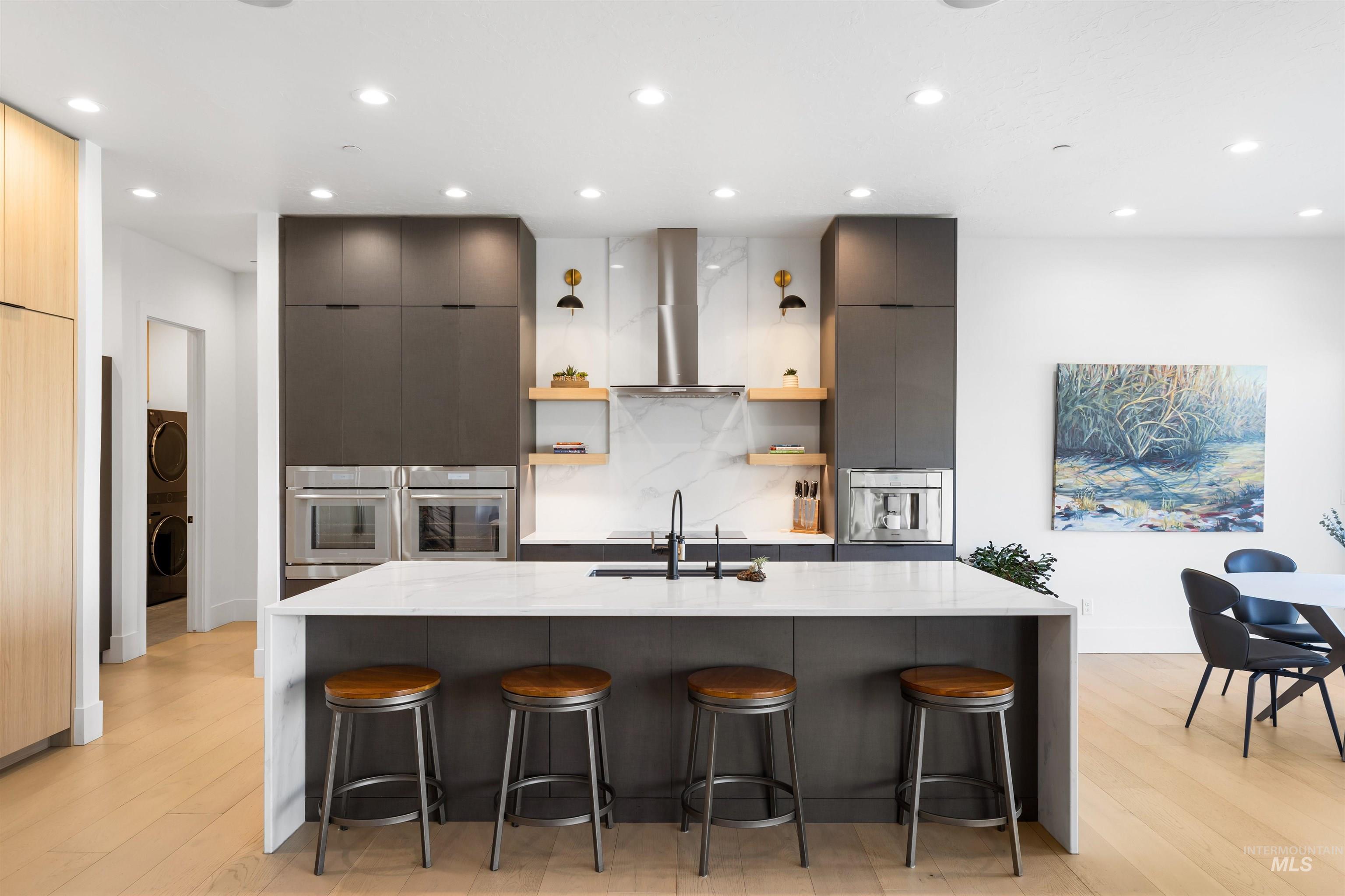 Kitchen with modern cabinets, a breakfast bar, recessed lighting, light wood finished floors, and light stone counters