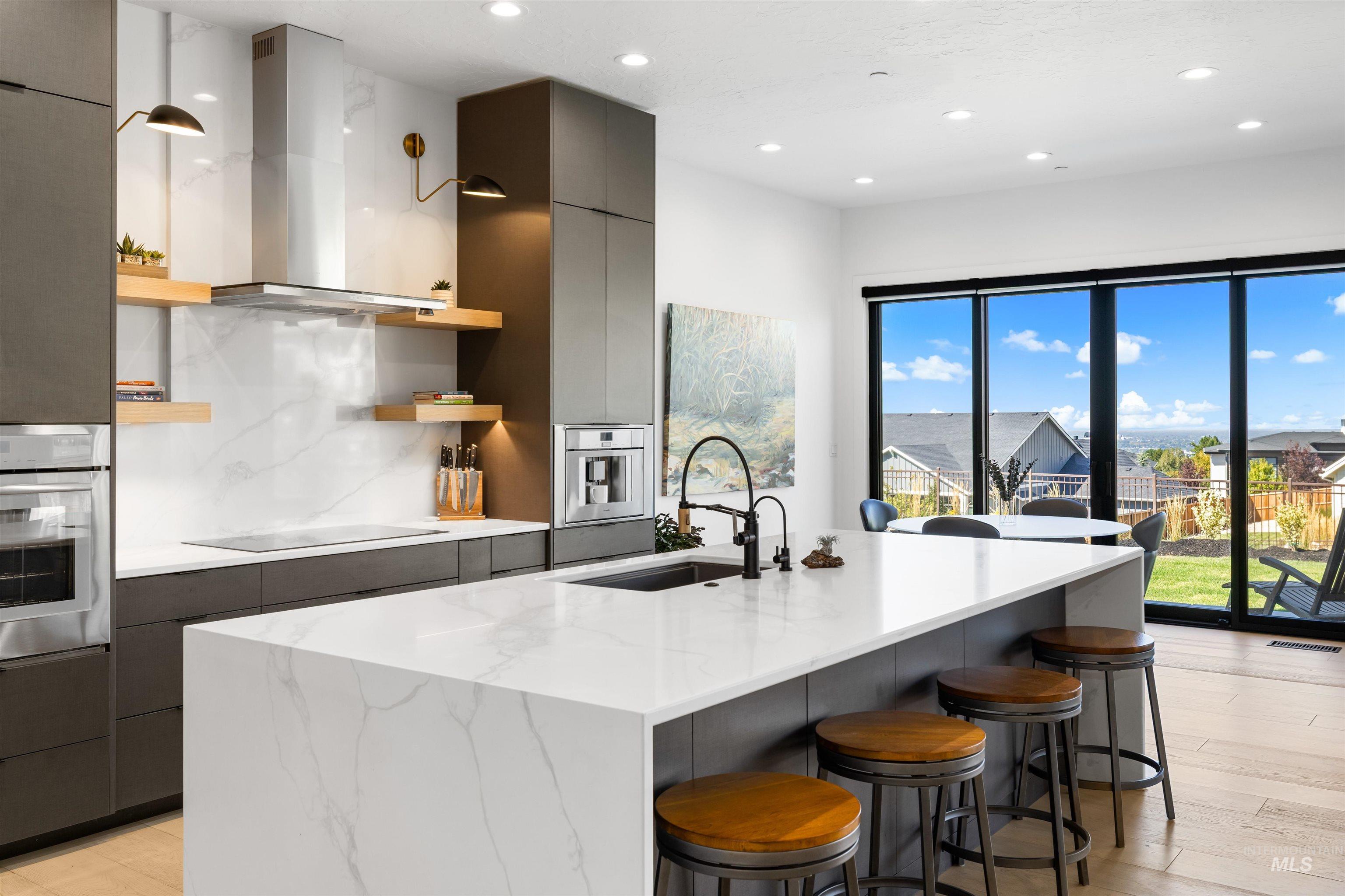 Kitchen featuring modern cabinets, oven, tasteful backsplash, a kitchen bar, and an island with sink