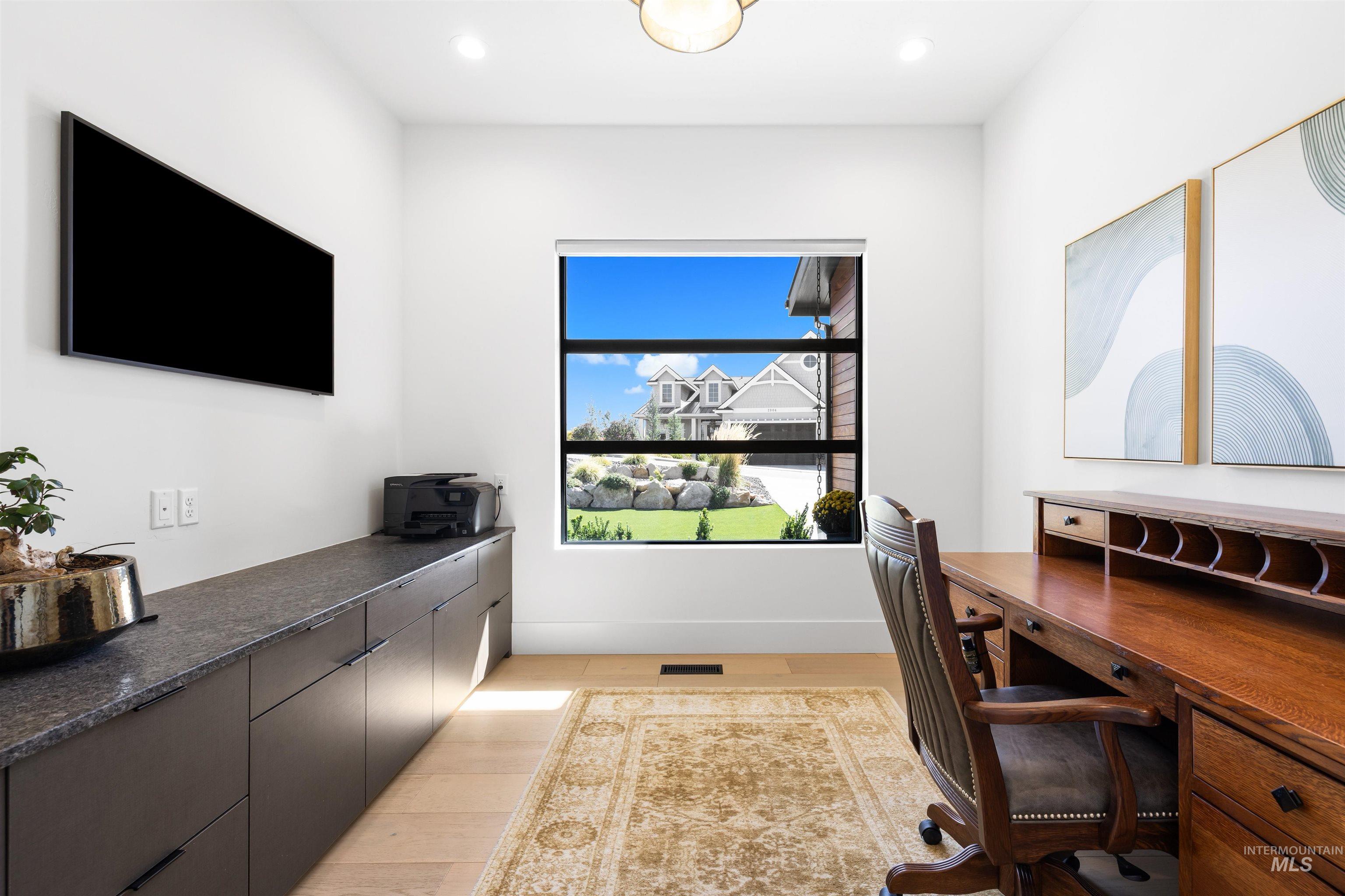 Home office with light wood-style flooring and recessed lighting