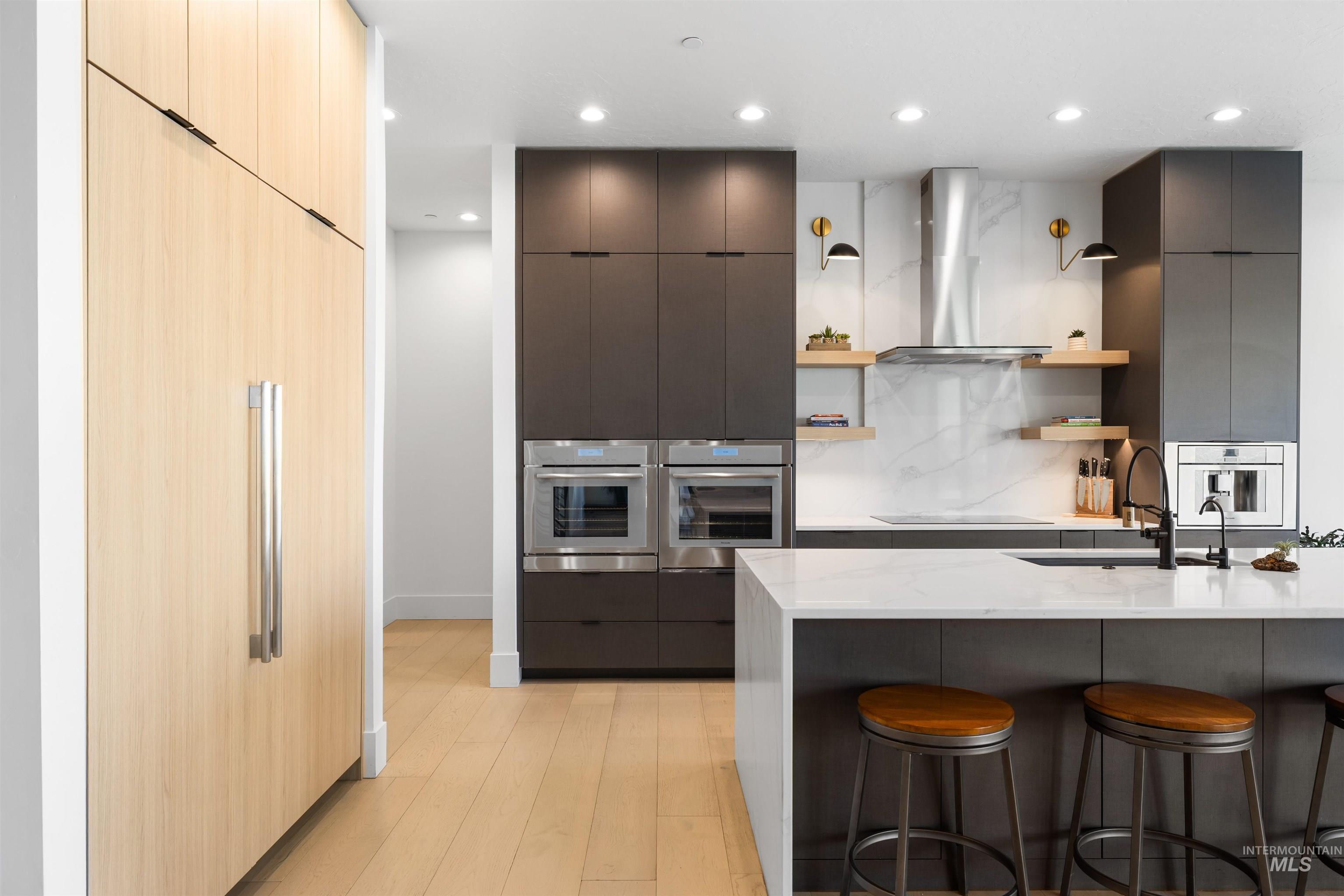 Kitchen featuring modern cabinets, open shelves, paneled refrigerator, a breakfast bar area, and recessed lighting