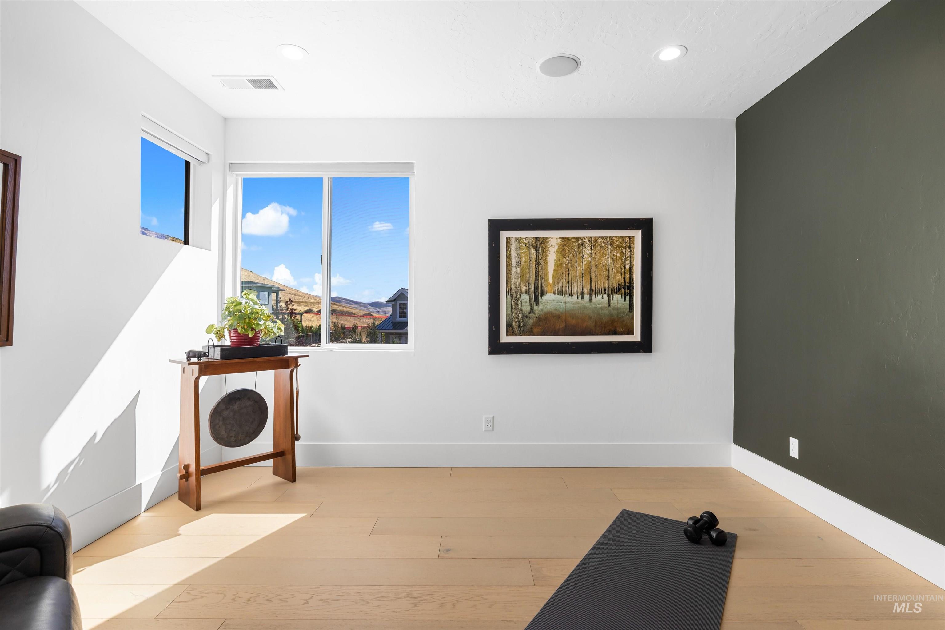 Exercise area with light wood-style flooring and recessed lighting