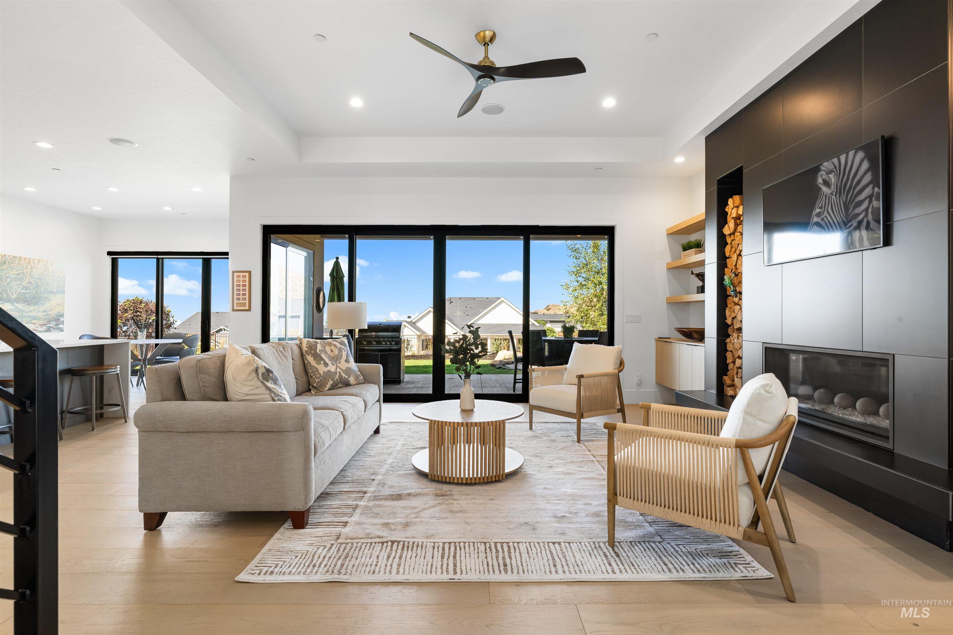 Living room featuring a fireplace, healthy amount of natural light, ceiling fan, light wood-style flooring, and recessed lighting