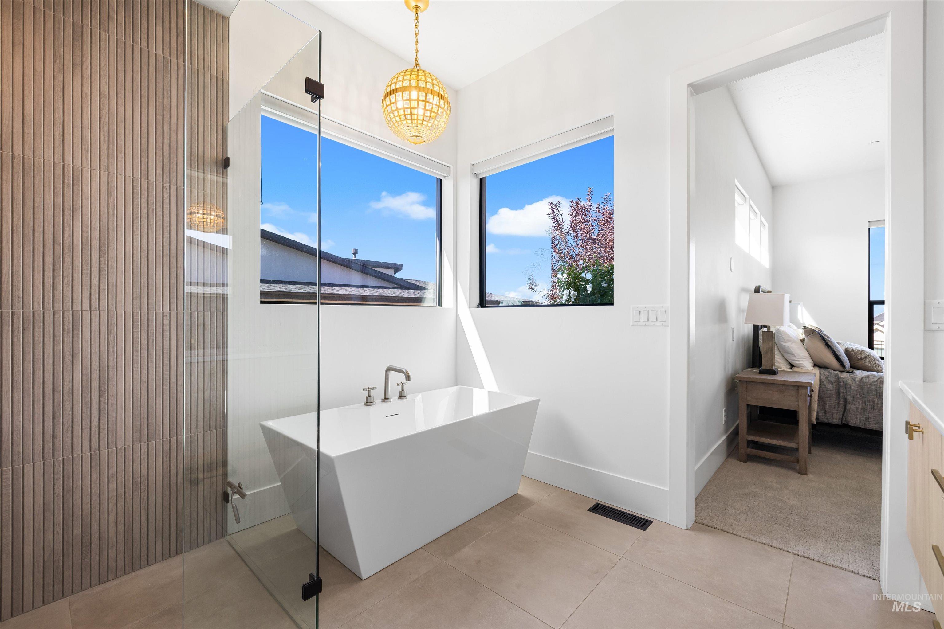 Ensuite bathroom with a soaking tub, light tile patterned flooring, and walk in shower
