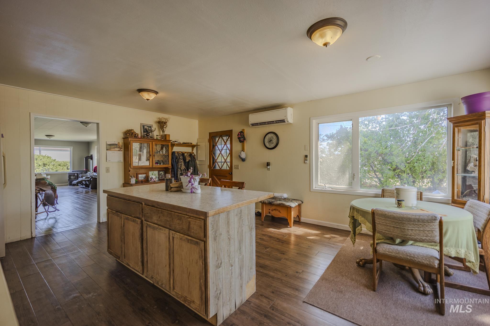 Kitchen featuring dark wood-style floors, light countertops, brown cabinets, a center island, and an AC wall unit