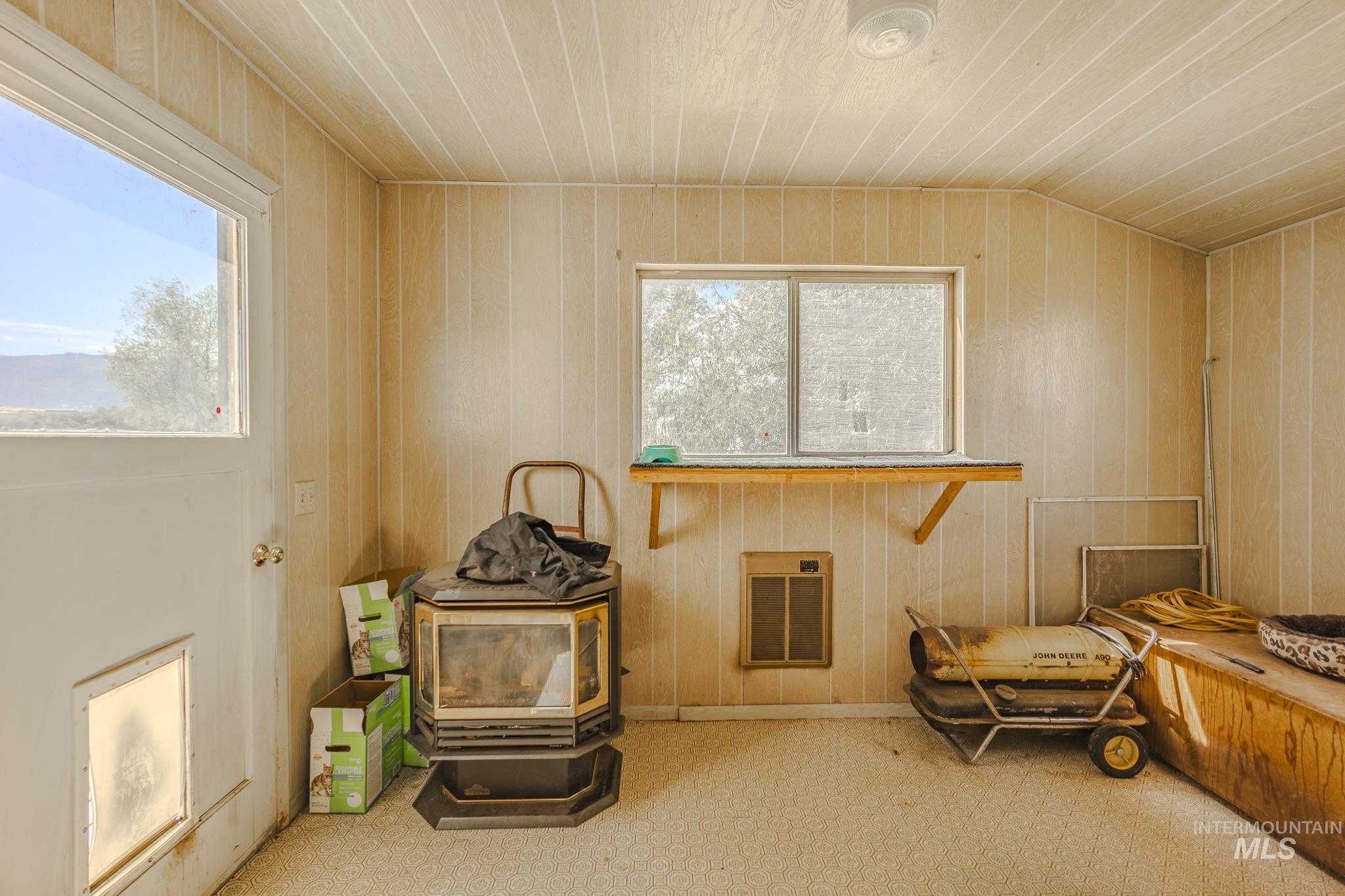 Sitting room featuring a wood stove, wooden walls, heating unit, and wooden ceiling