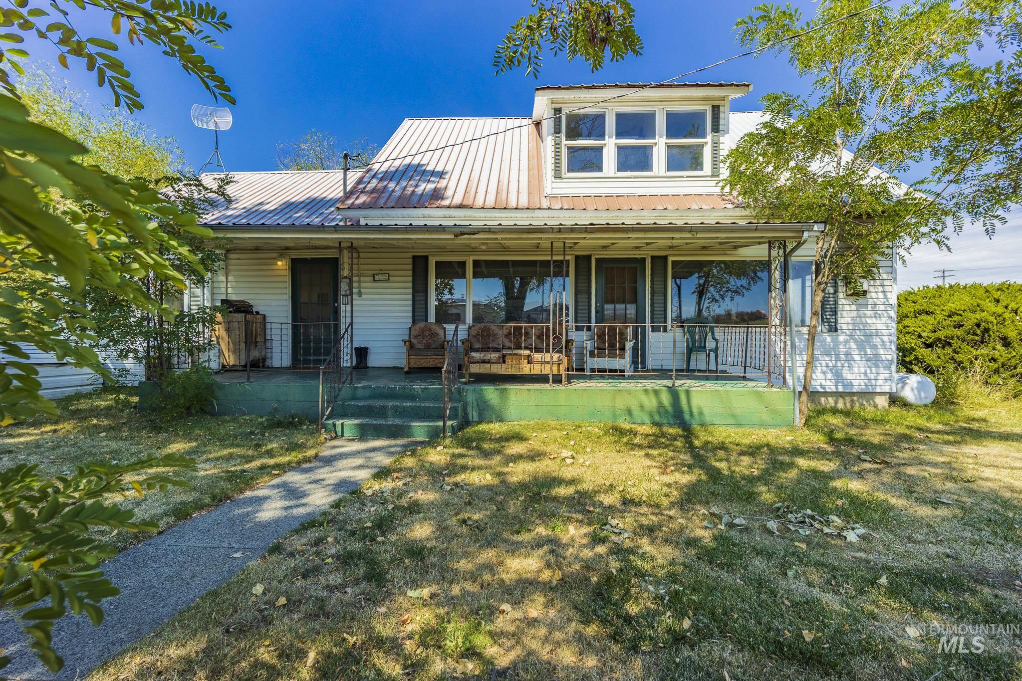 Farmhouse-style home featuring a porch, a front yard, and a metal roof