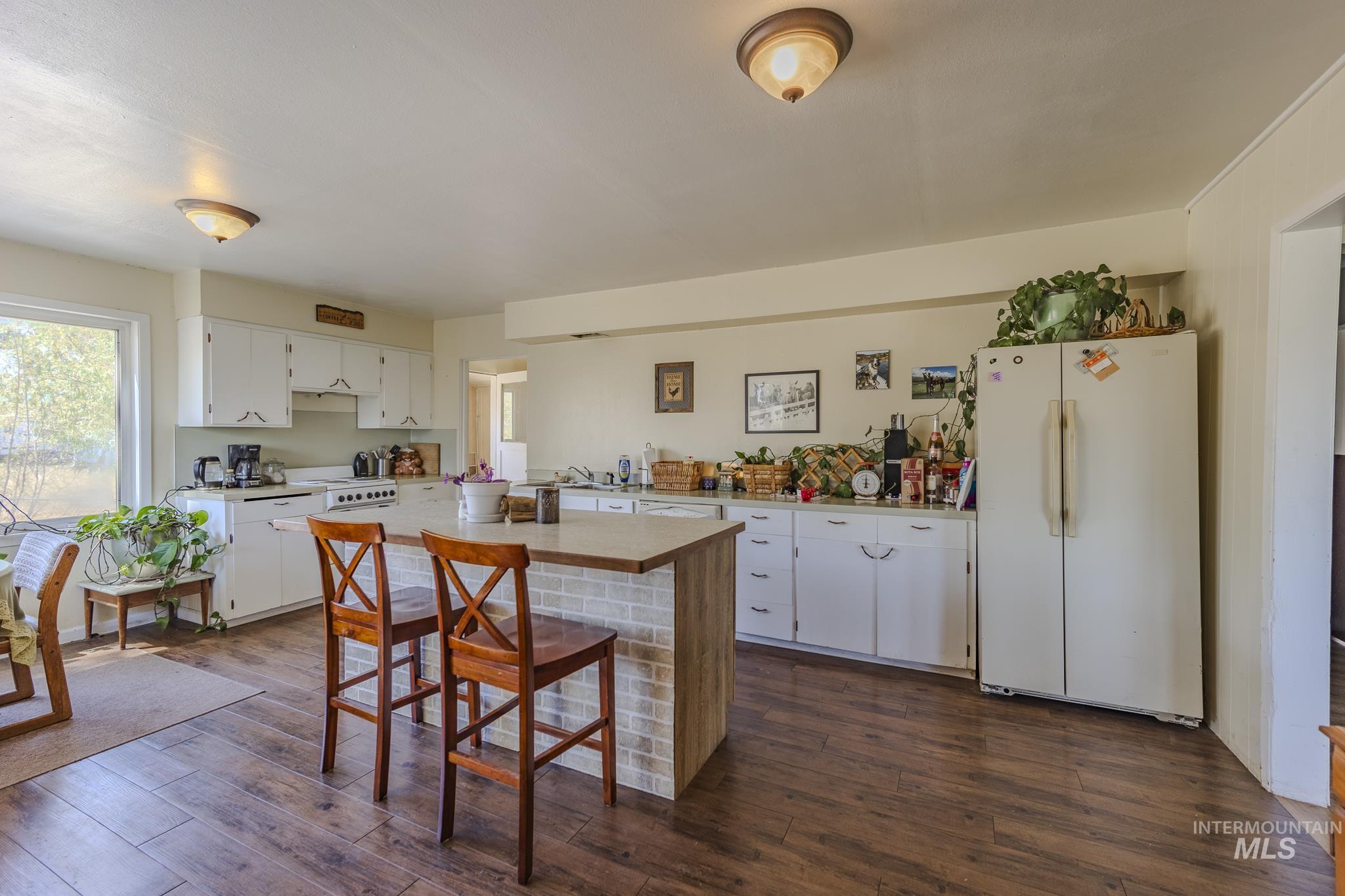 Kitchen featuring white appliances, light countertops, white cabinetry, and a kitchen breakfast bar
