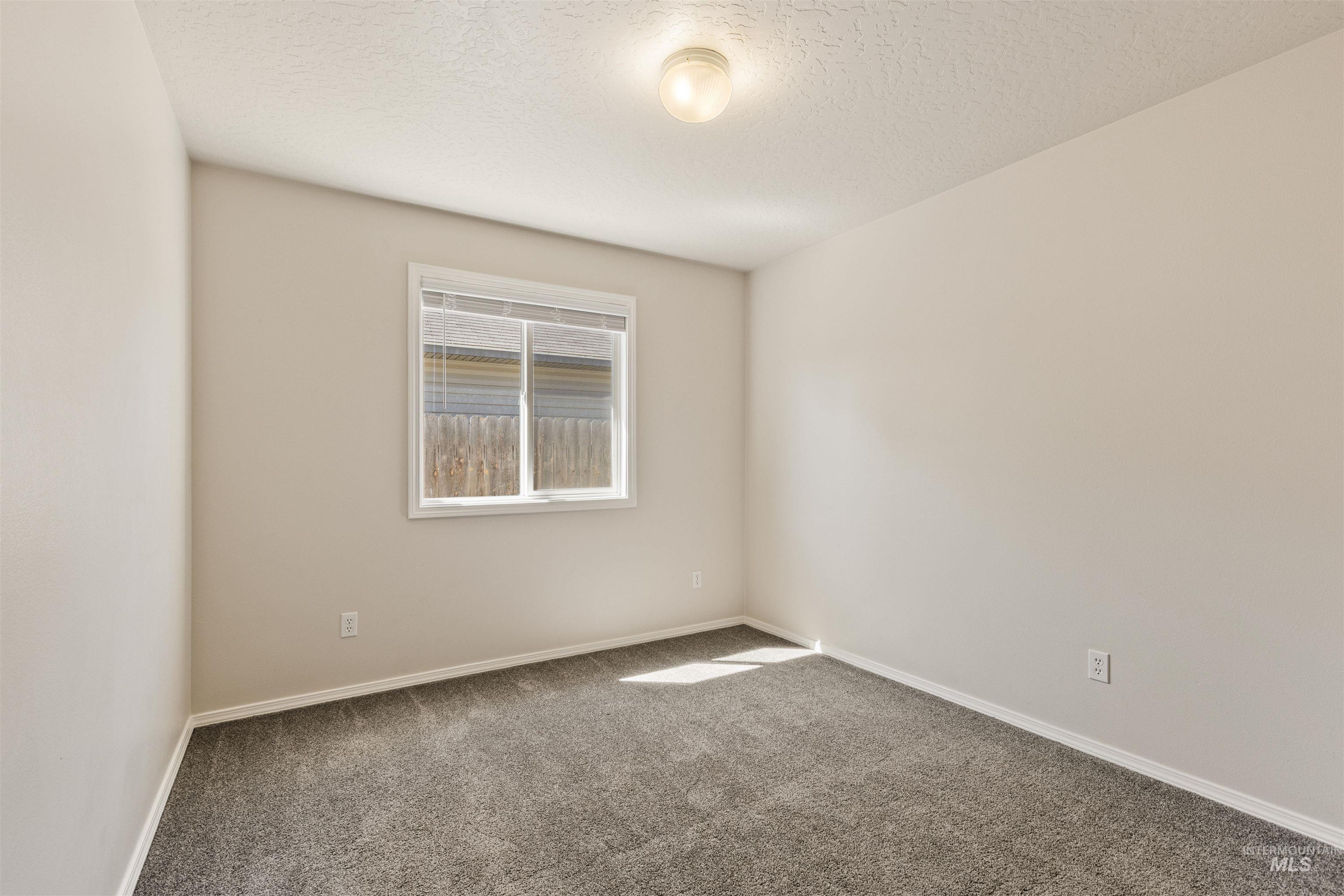 Empty room featuring carpet and a textured ceiling