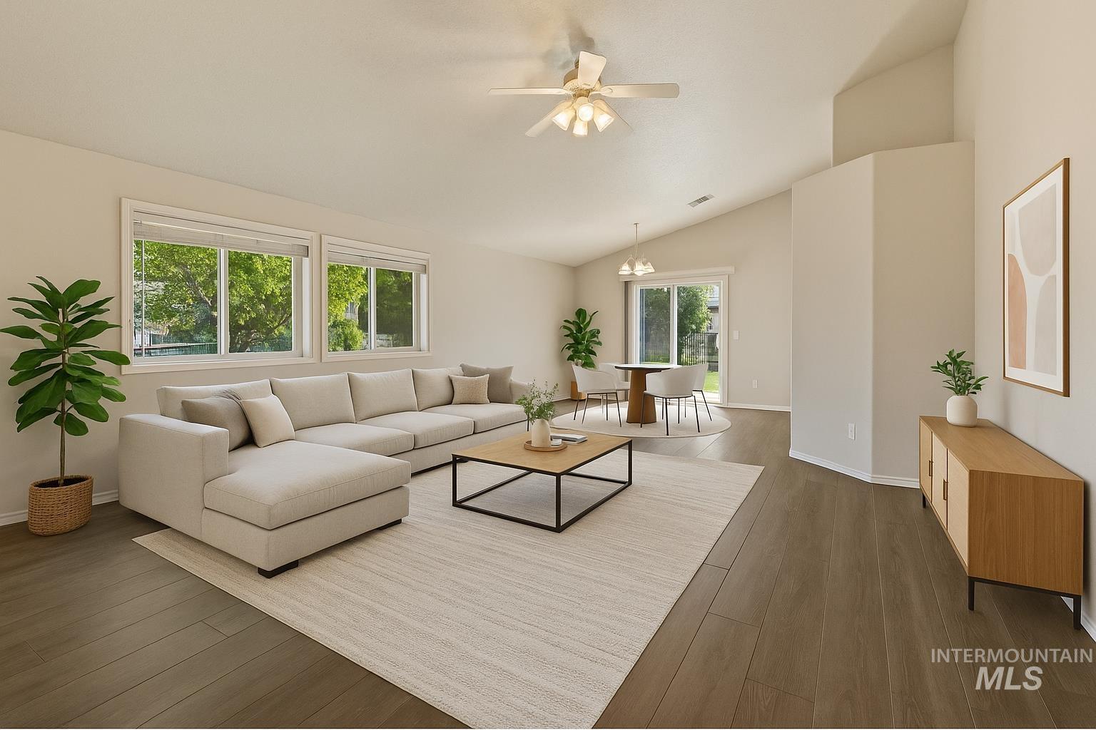 Living area featuring dark wood-type flooring, vaulted ceiling, a chandelier, and a ceiling fan