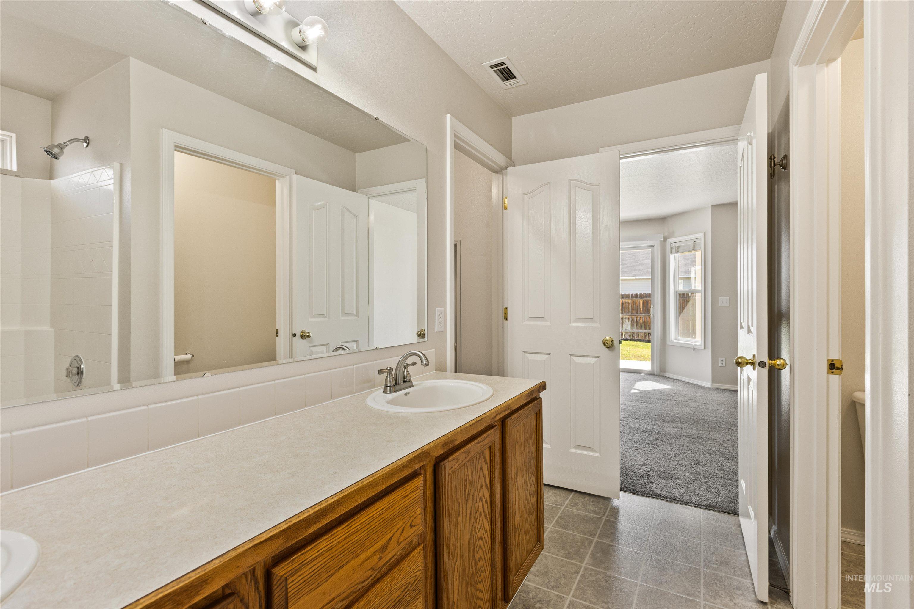Bathroom featuring vanity, dark tile patterned flooring, and a textured ceiling