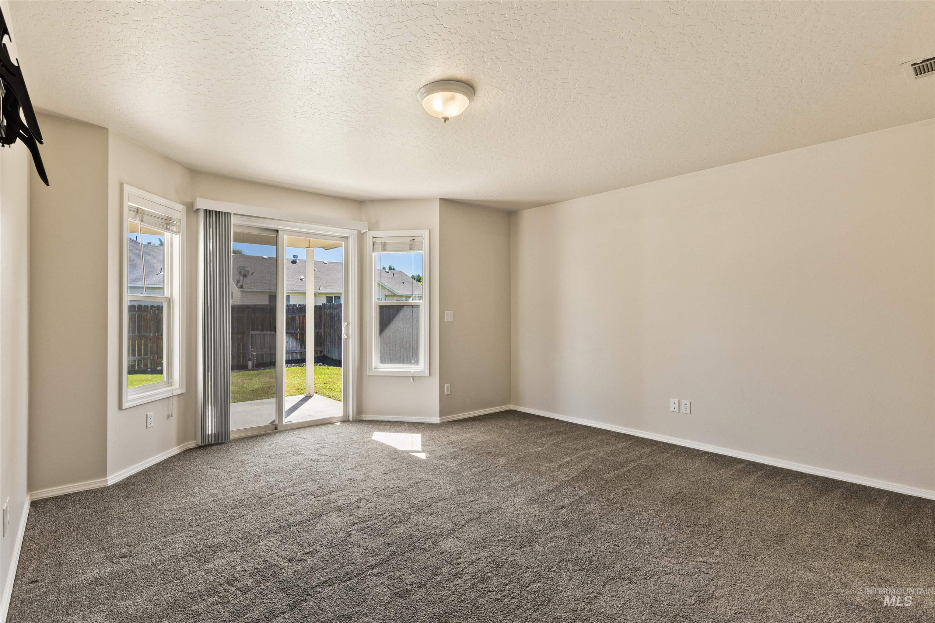 Empty room featuring a textured ceiling and dark carpet