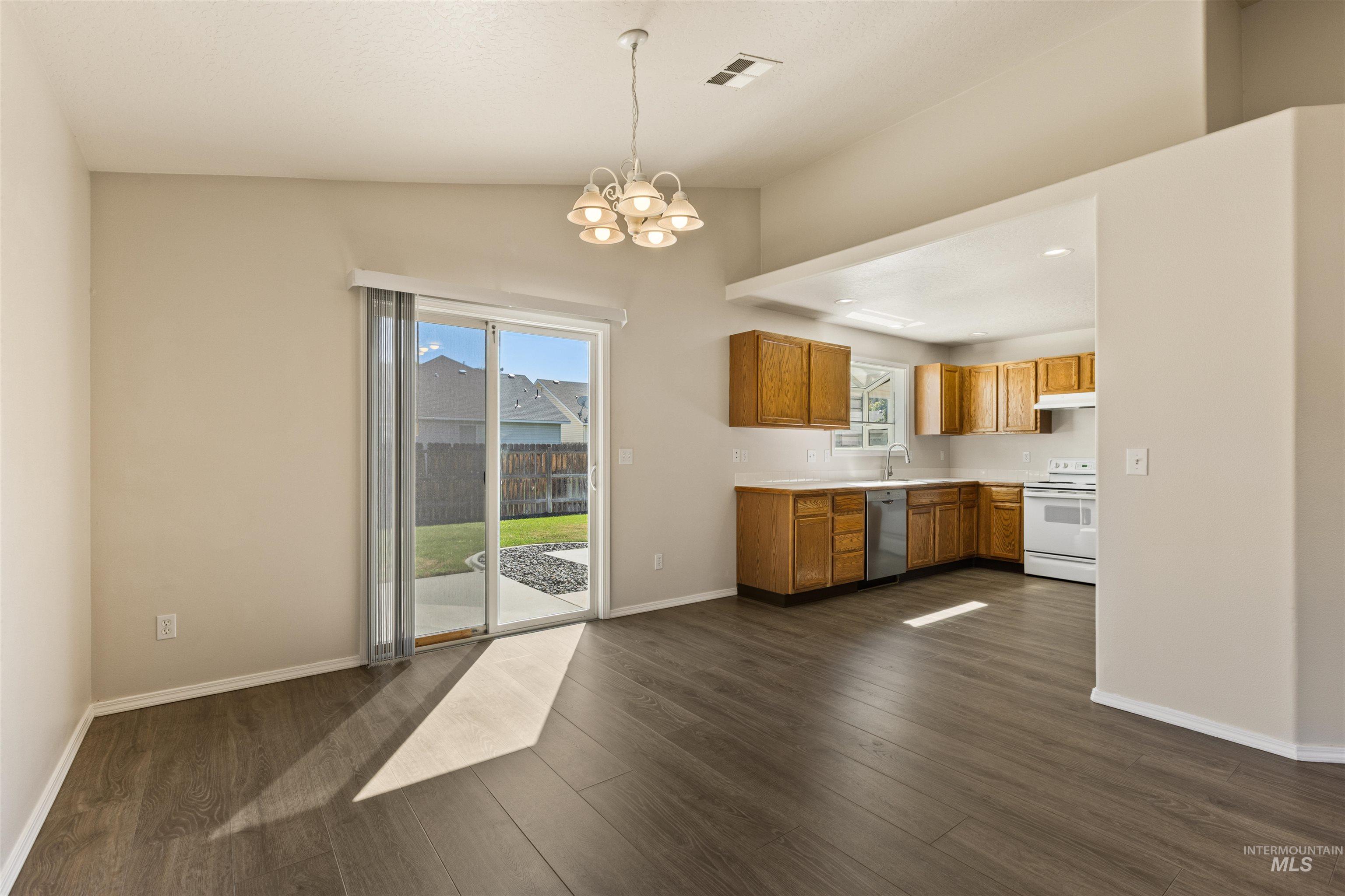 Kitchen featuring light countertops, decorative light fixtures, a chandelier, dark wood-style flooring, and electric range