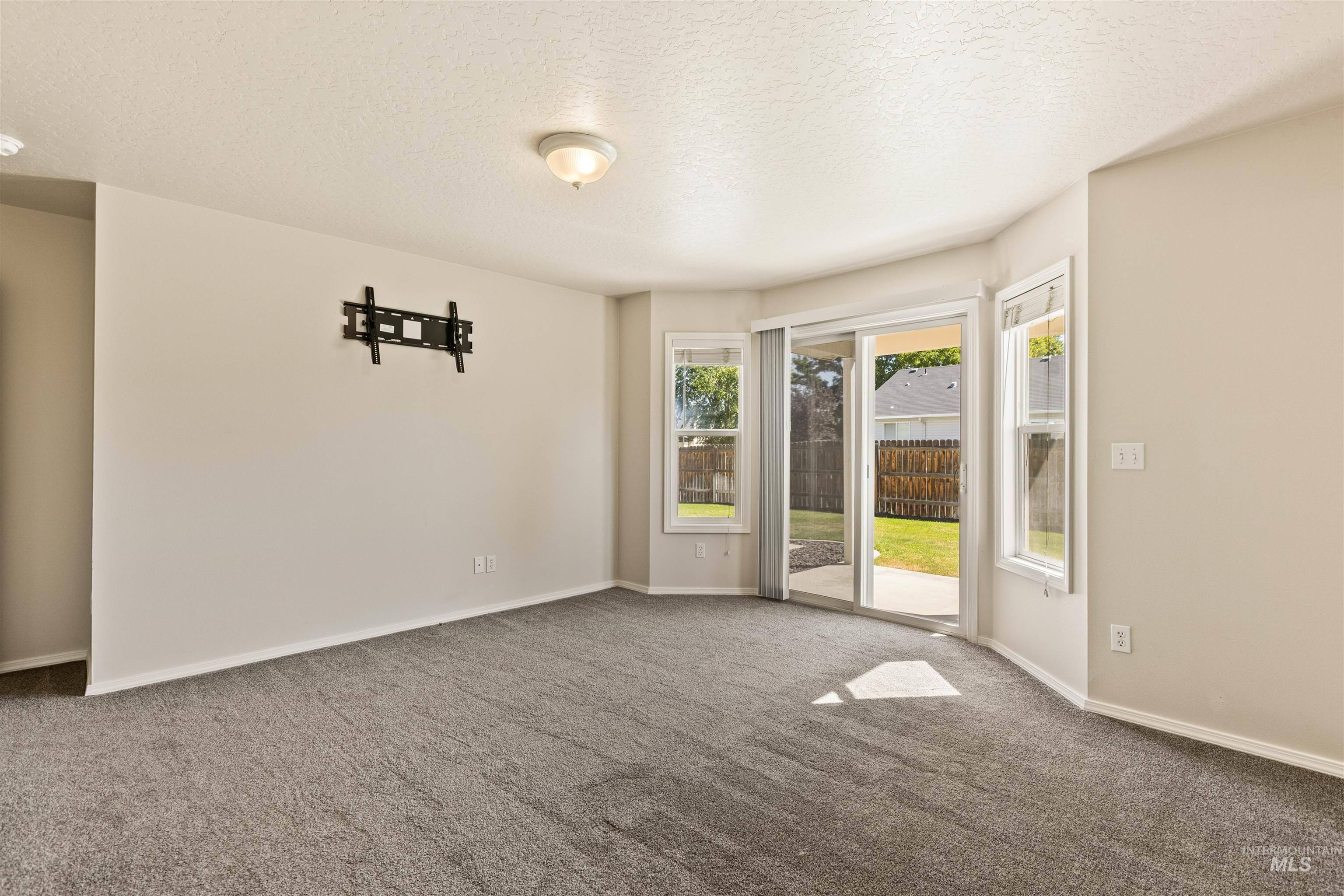 Empty room featuring a textured ceiling and carpet flooring