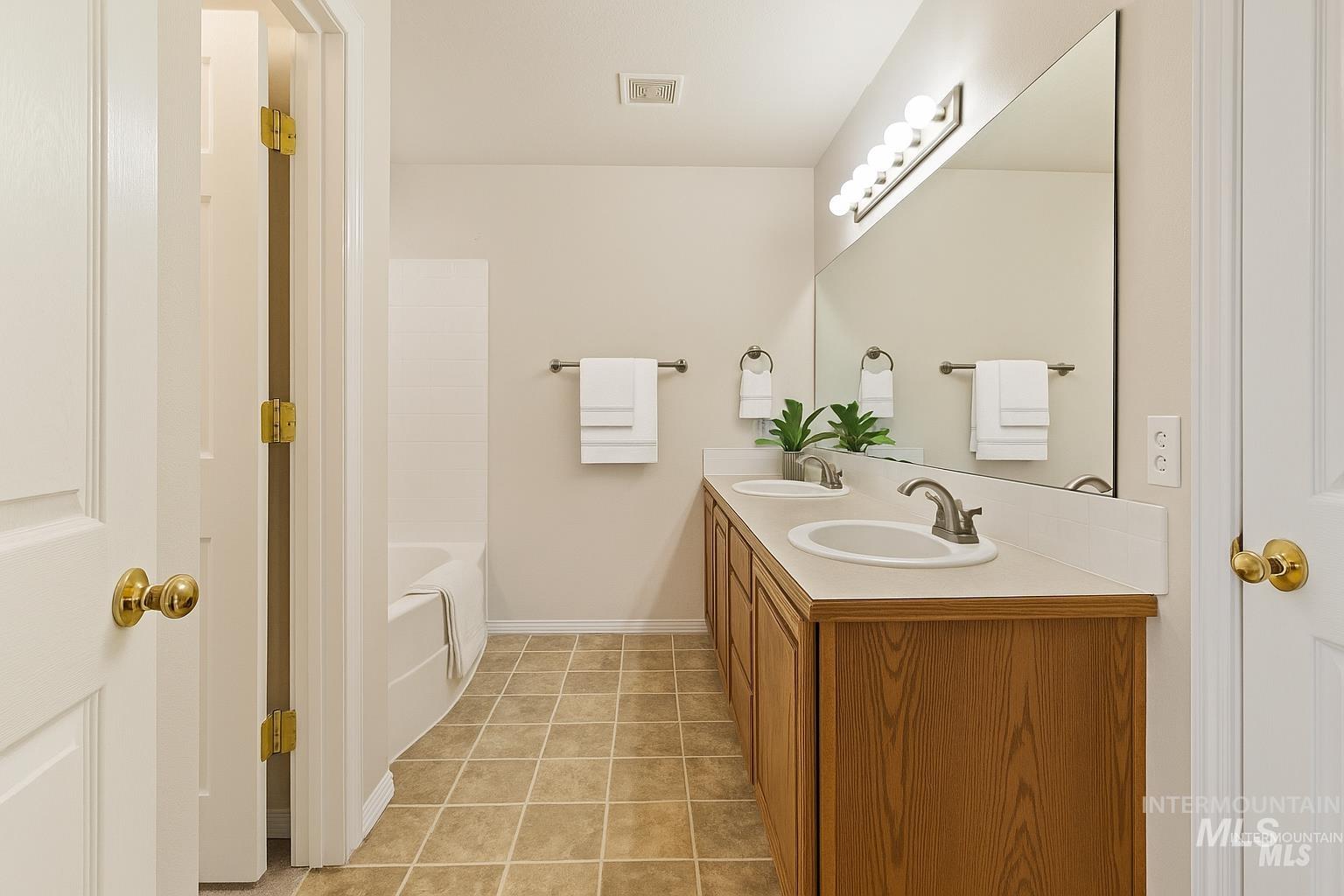 Bathroom with light tile patterned floors and double vanity