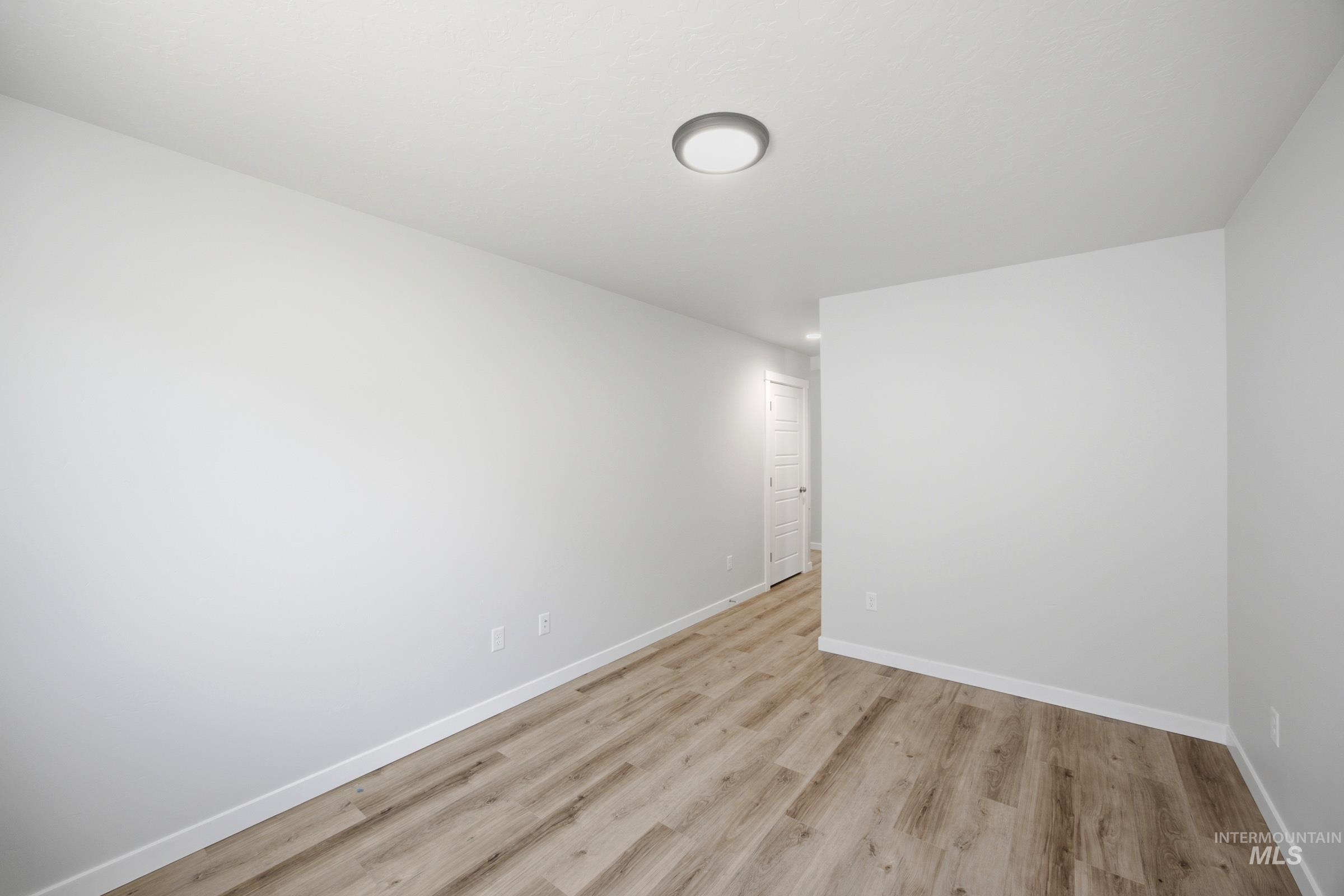 Room featuring wood-finish flooring, white baseboards, and neutral wall paint