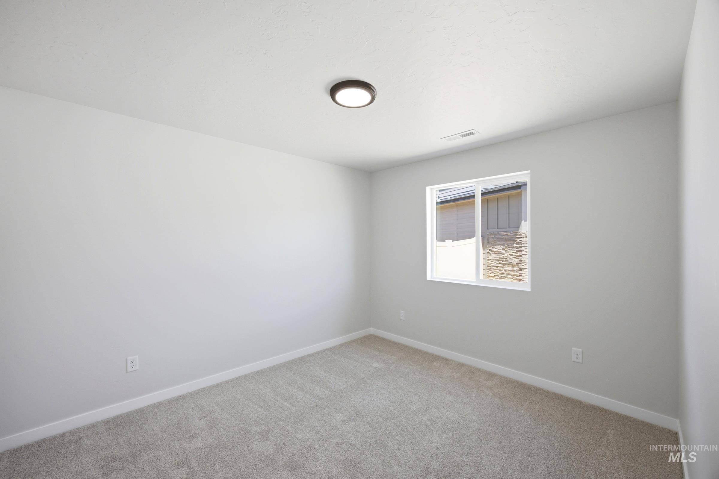 Light gray carpeted room featuring a single window and flush-mount ceiling light