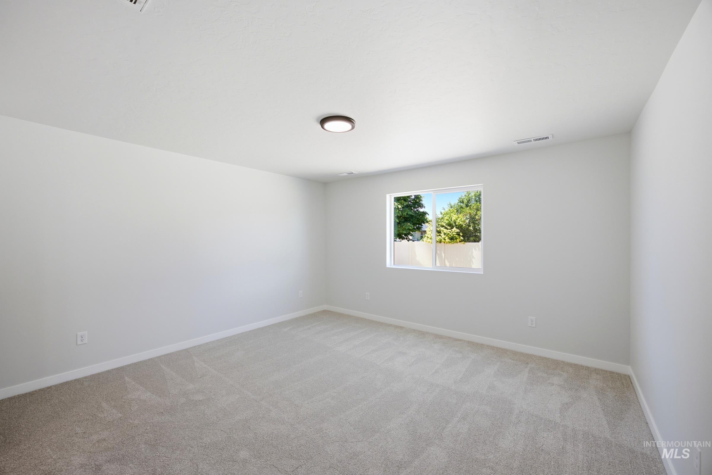 Spacious room with light-toned carpet flooring and white baseboards