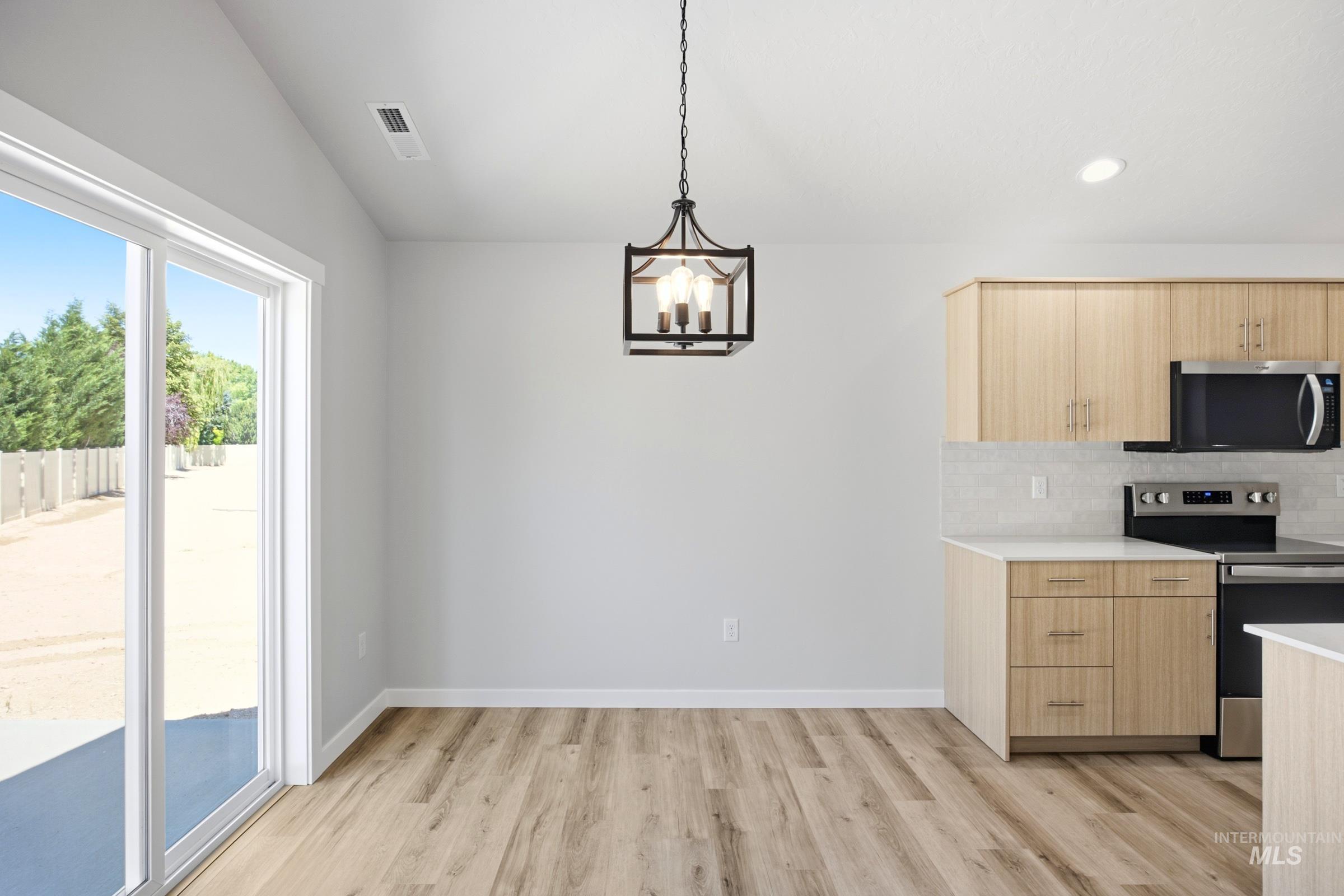 Open-concept living space featuring wood-finish flooring, a contemporary chandelier, and a sliding glass door