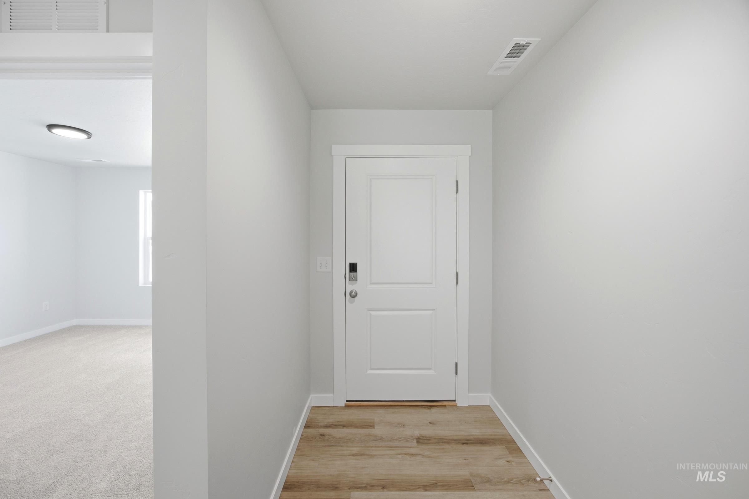 Entryway featuring wood-finish flooring, a two-panel door with modern hardware, and neutral wall tones