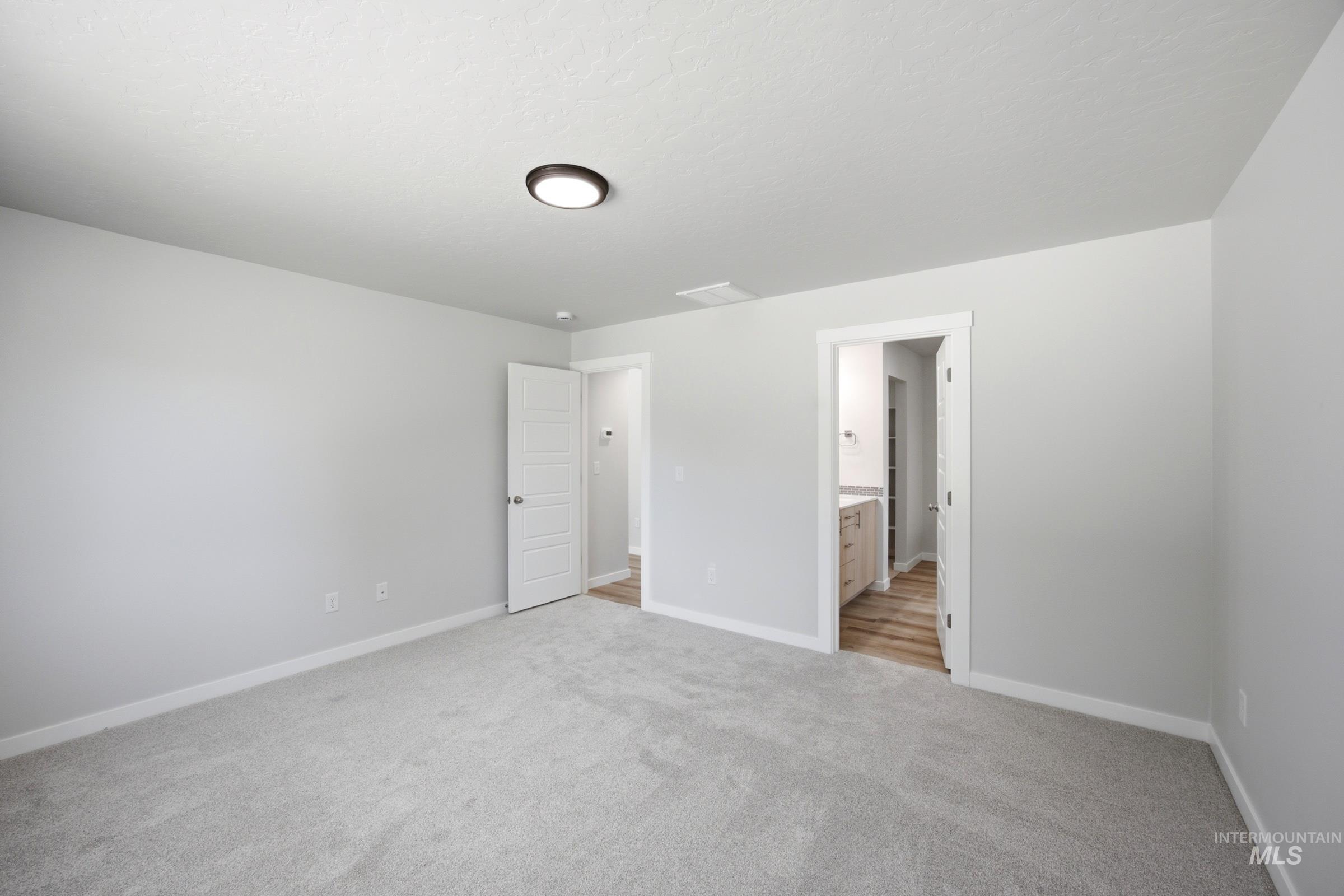 Carpeted room featuring light gray walls, white trim, and a flush-mount ceiling light