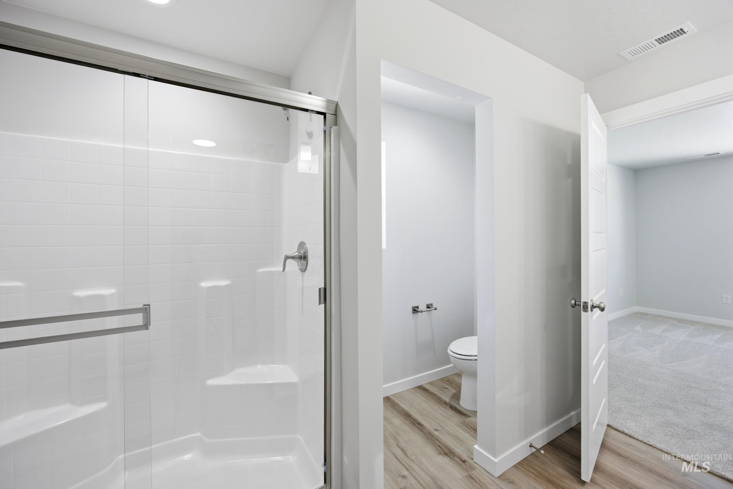 Shower enclosure with clear glass doors, white subway tile-patterned surround, and built-in shelving