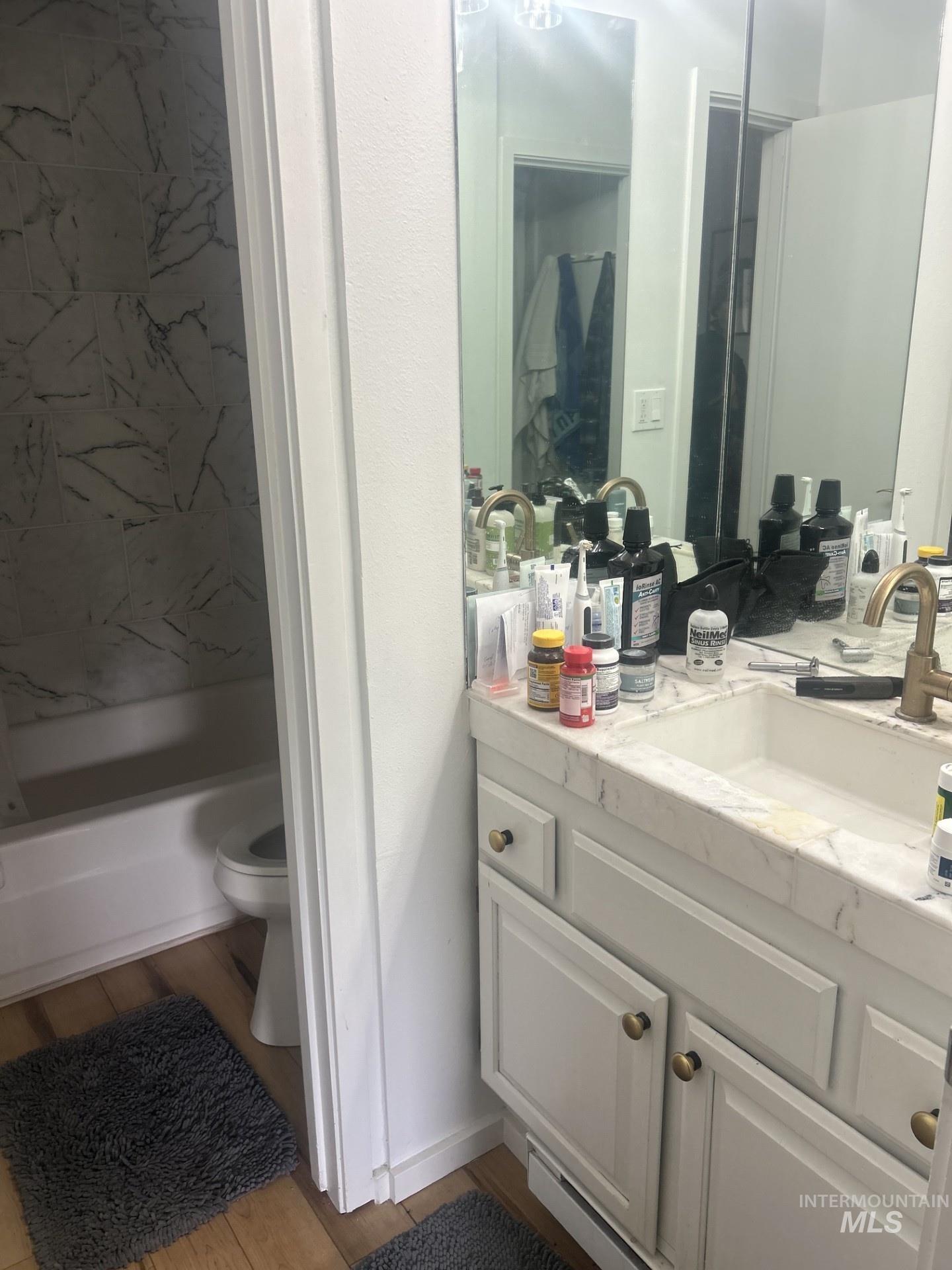 White vanity with a light-colored countertop and brass-finish hardware