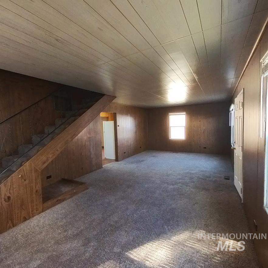 Bonus room featuring carpet floors, wood walls, wood ceiling, and stairs