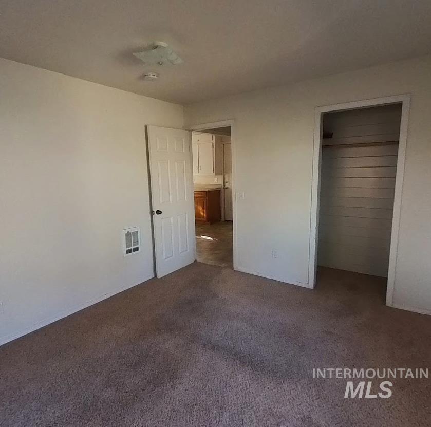 Unfurnished bedroom with dark colored carpet and a closet
