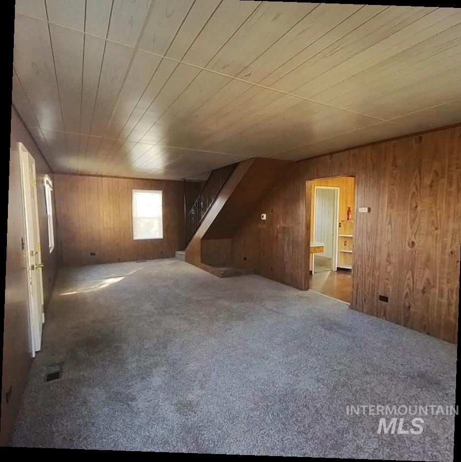 Bonus room featuring carpet, wood walls, stairway, and wood ceiling