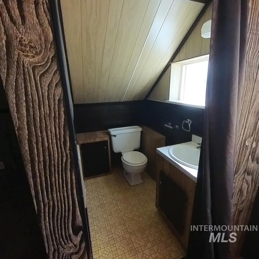 Half bath featuring vanity, vaulted ceiling, wooden ceiling, and light flooring