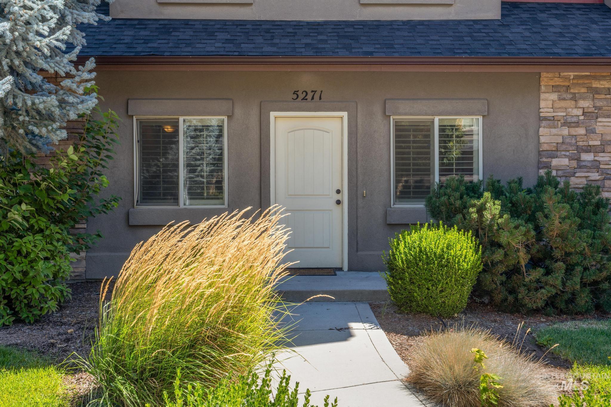 View of exterior entry featuring a shingled roof, stucco siding, and stone siding