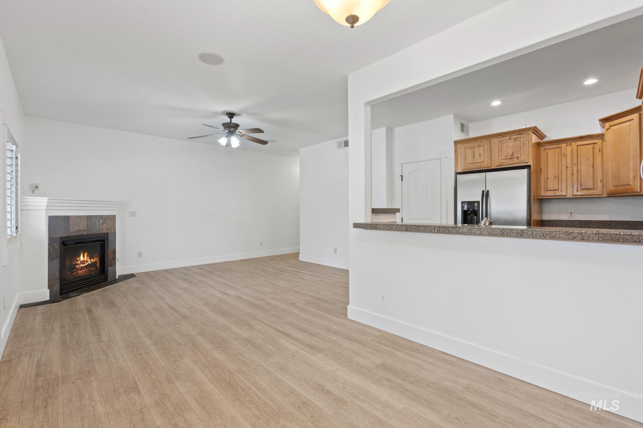 Unfurnished living room with light wood-type flooring, a fireplace, a ceiling fan, and recessed lighting