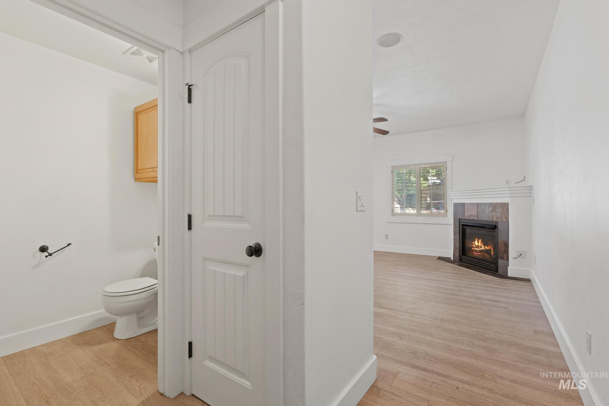 Bathroom with light wood-style floors, a fireplace, and a ceiling fan