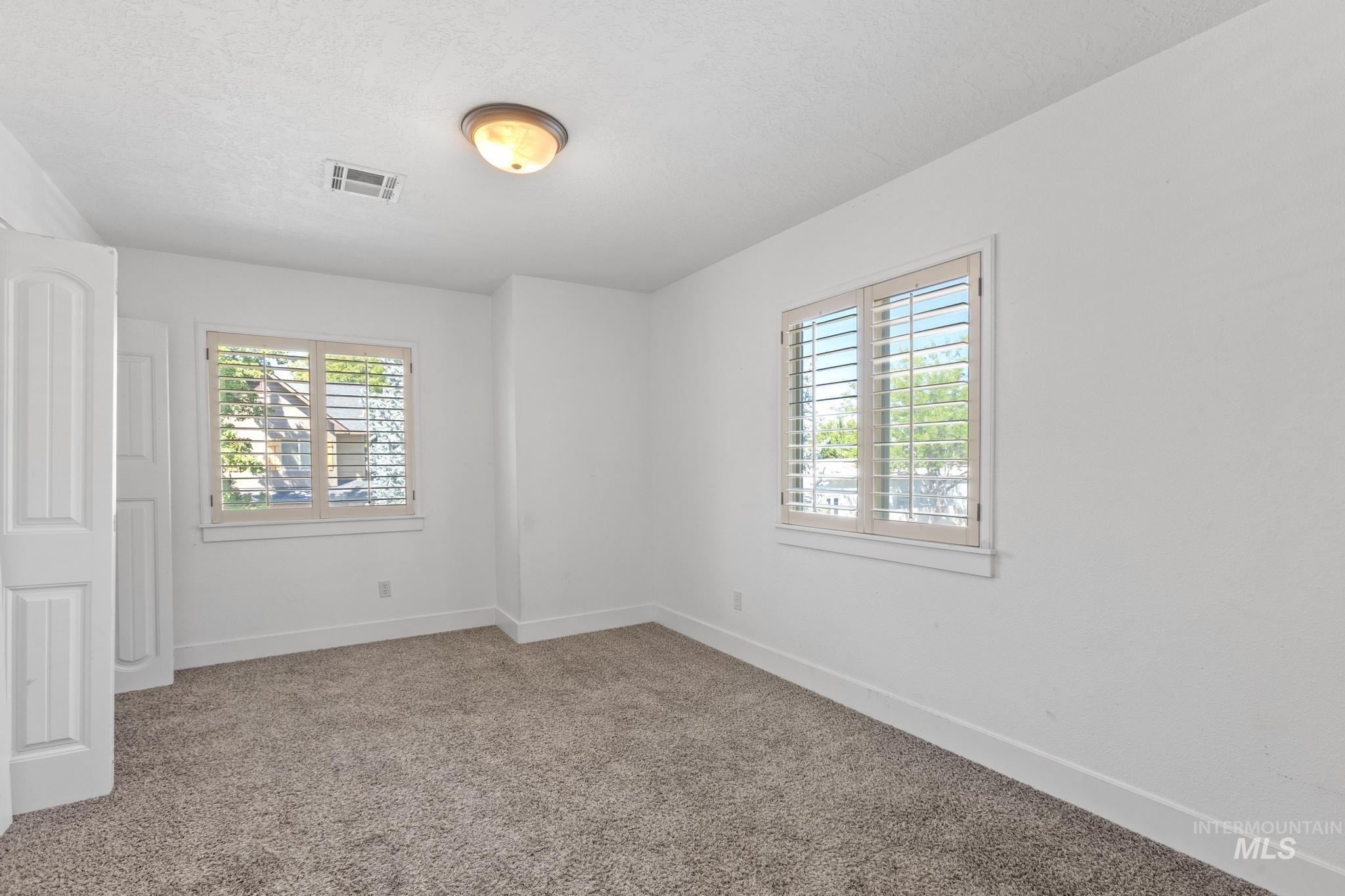 Unfurnished room featuring carpet floors, healthy amount of natural light, and a textured ceiling