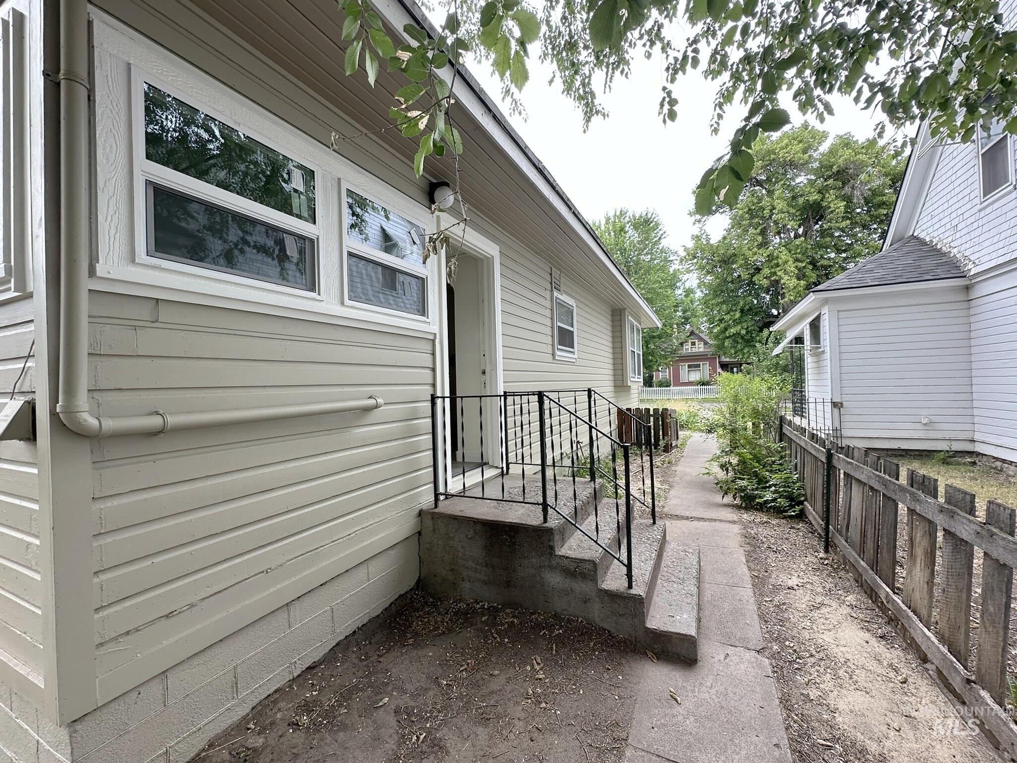Side exterior with horizontal siding, white trim windows, and a concrete pathway