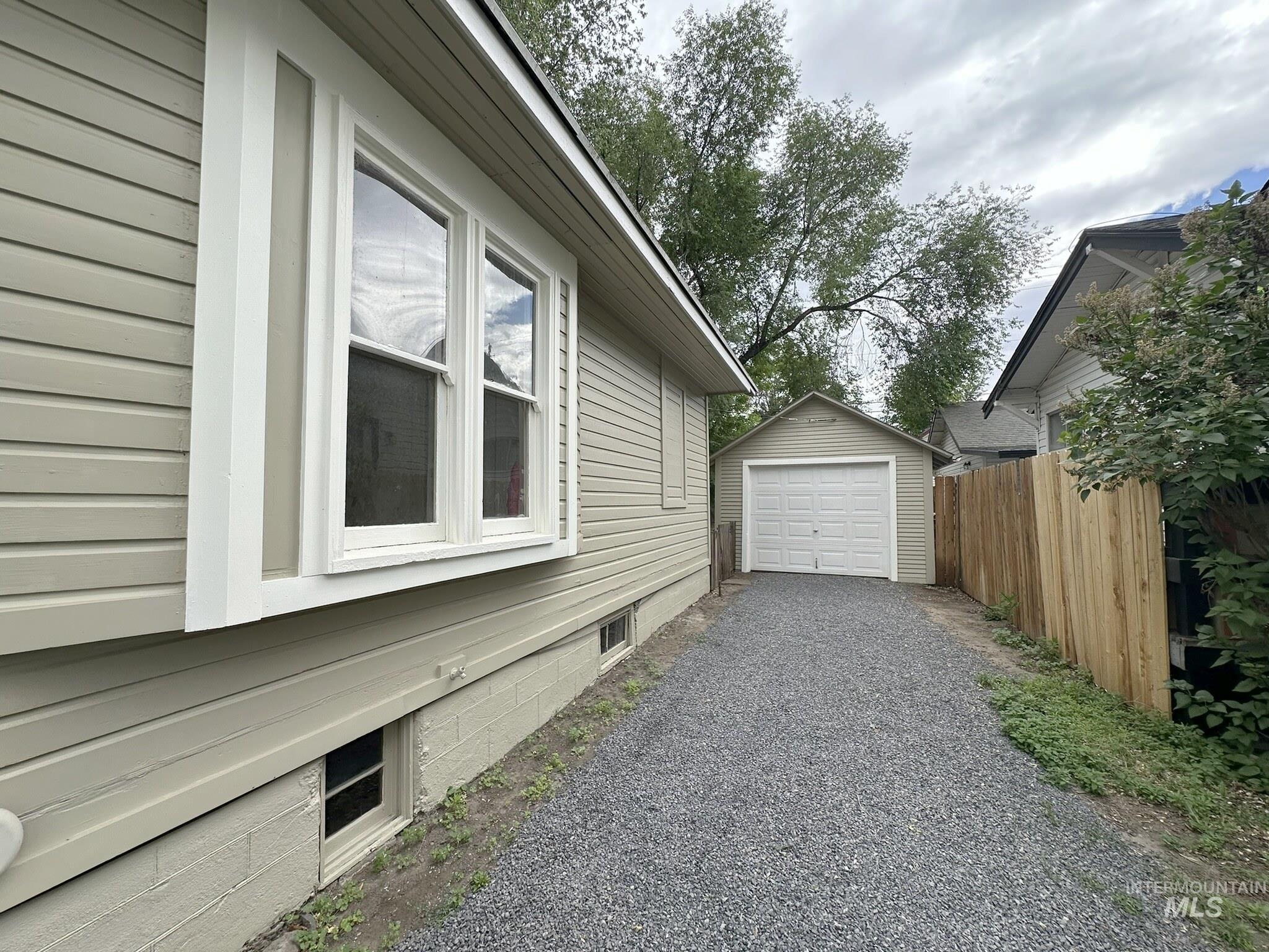 Gravel driveway leading to a detached single-car garage featuring a white overhead door