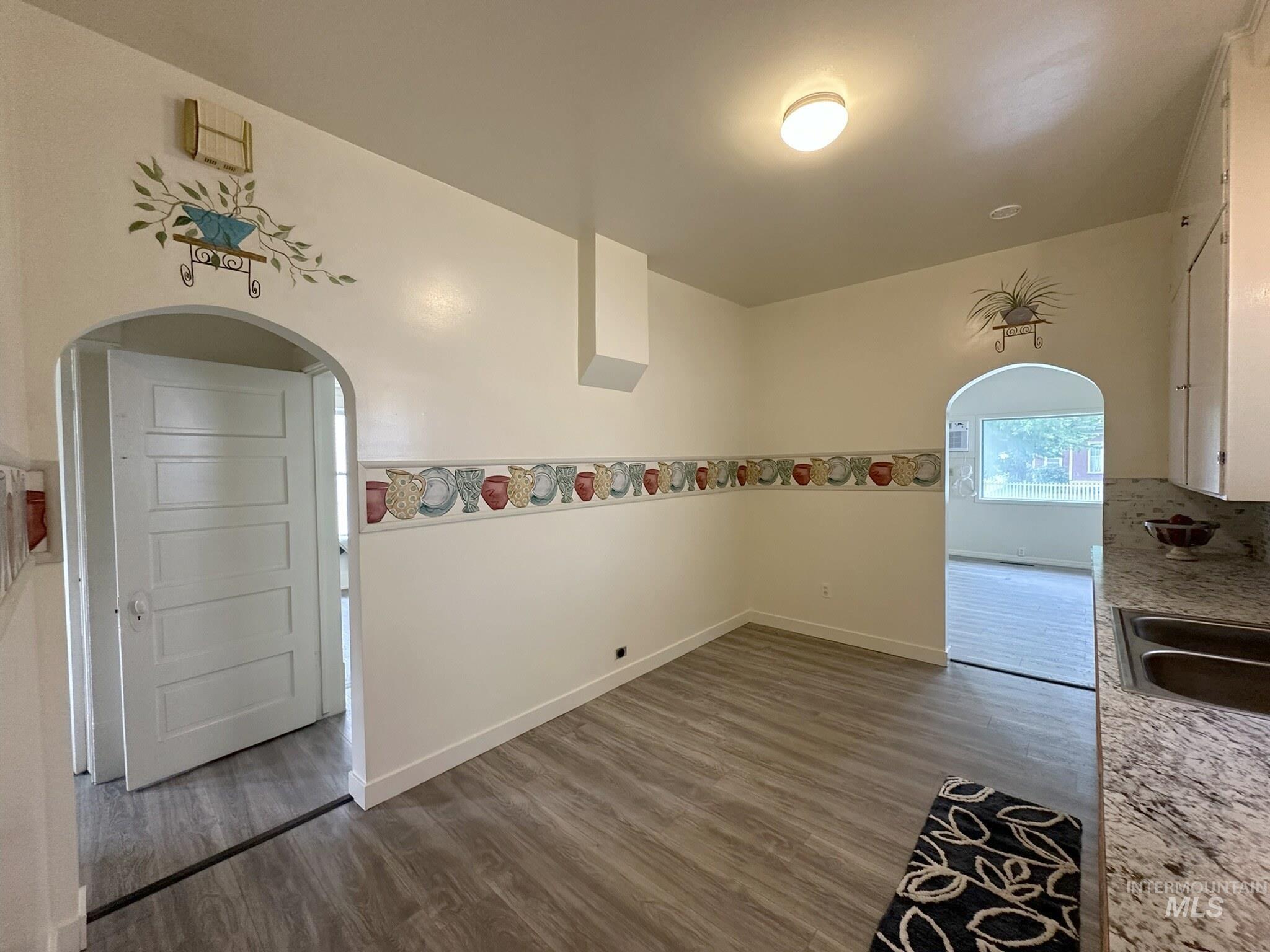 Dining area featuring wood-finish flooring and two arched doorways