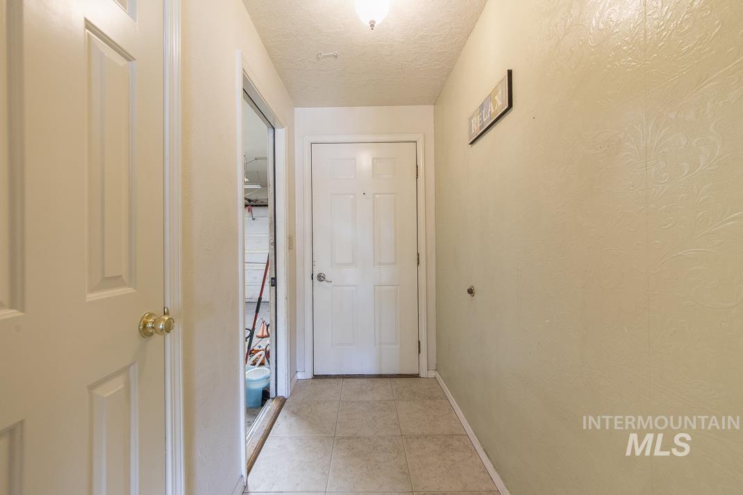 Hallway with light tile patterned floors and a textured ceiling